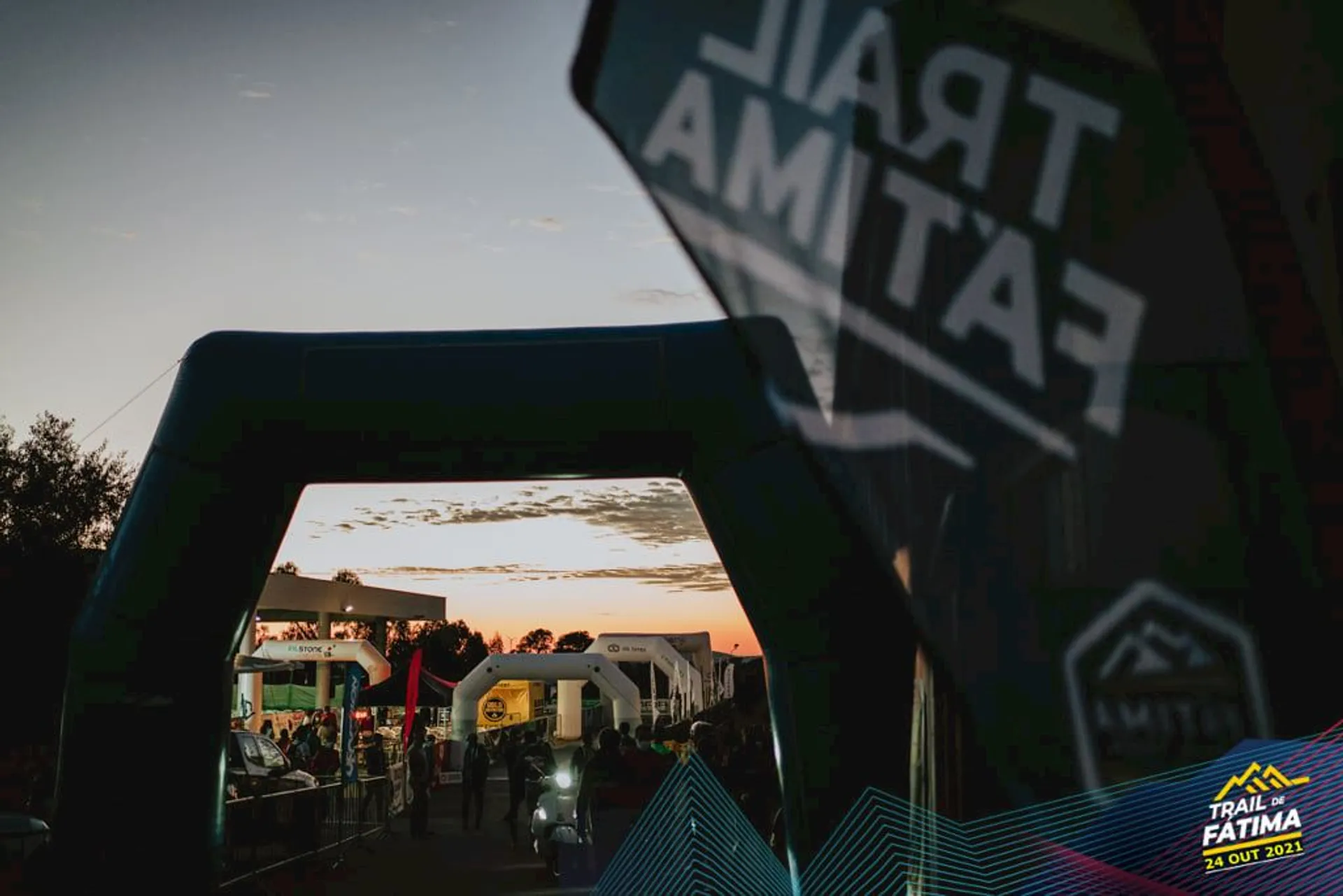 The image shows an outdoor event at dusk with a beautiful sunset in the background.