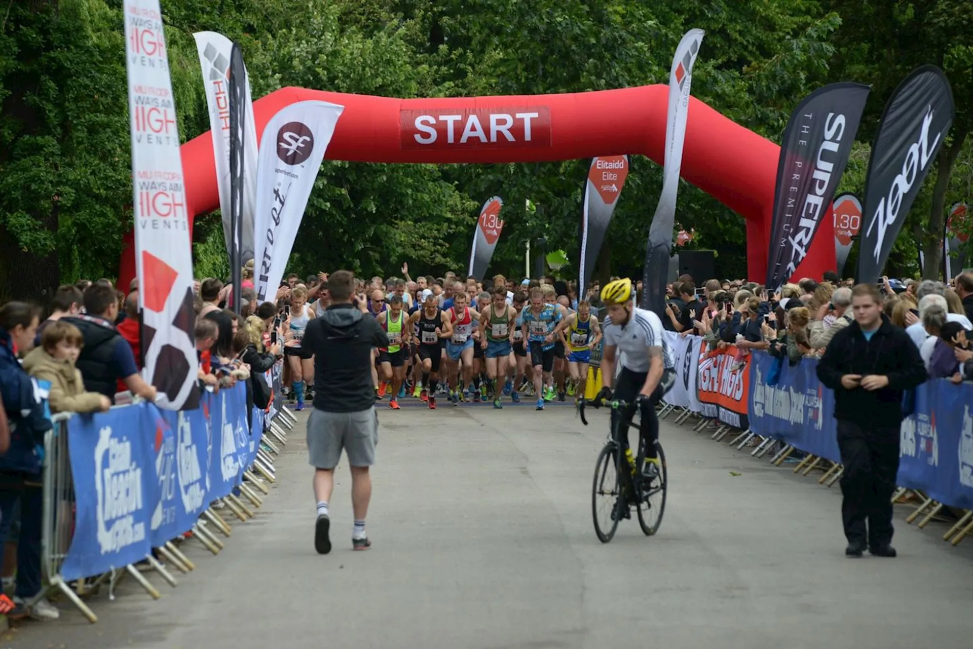 The image shows a road running event about to commence. Participants are gathered at the