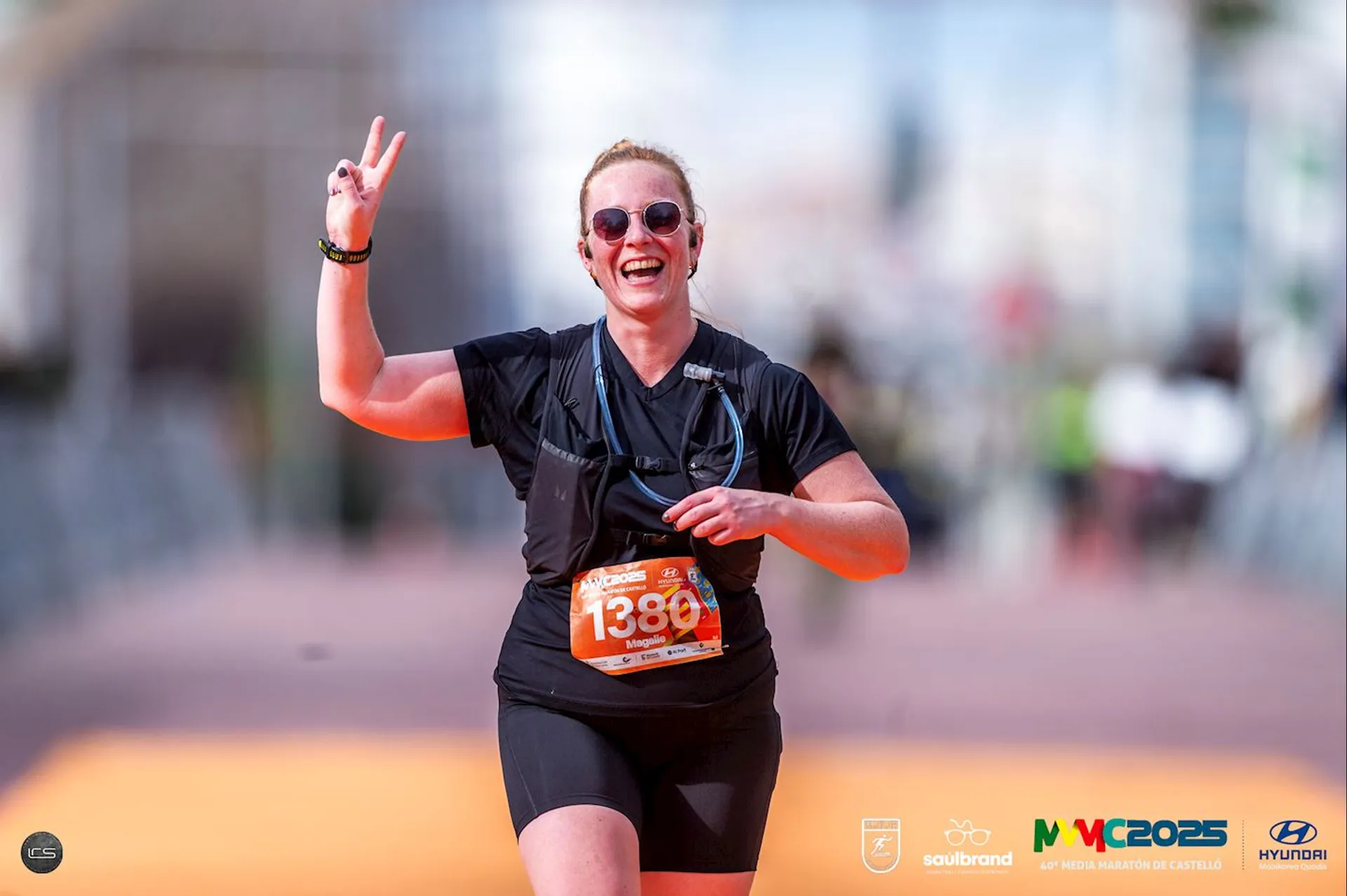 The image shows a person running, wearing sports attire and sunglasses, with a race bib that has the number 1380 on it. The person is smiling and making a peace sign gesture. The background includes logos, such as Soulbrand, MY2025, and Hyundai, indicating this is likely an organized running event or marathon.