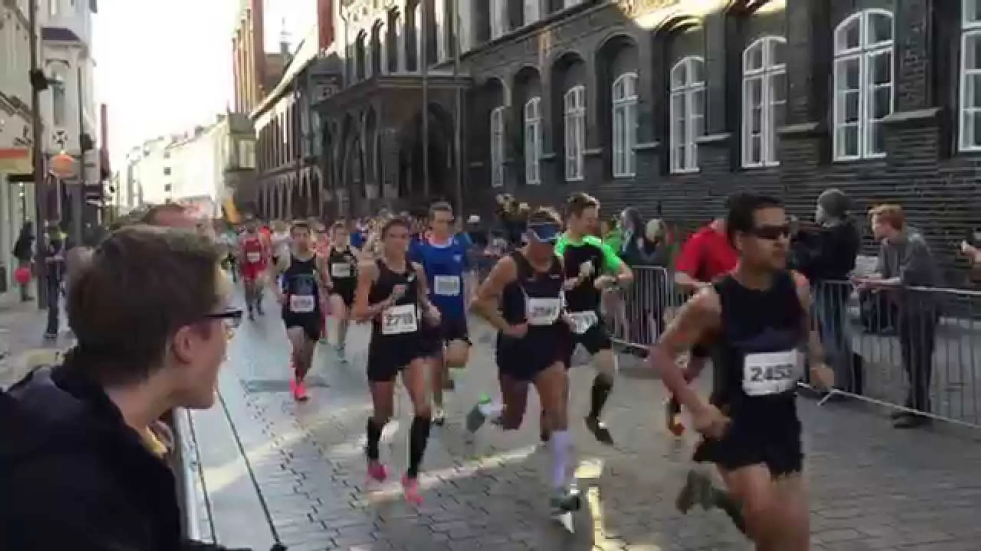The image shows a group of people participating in a road race, likely a marathon