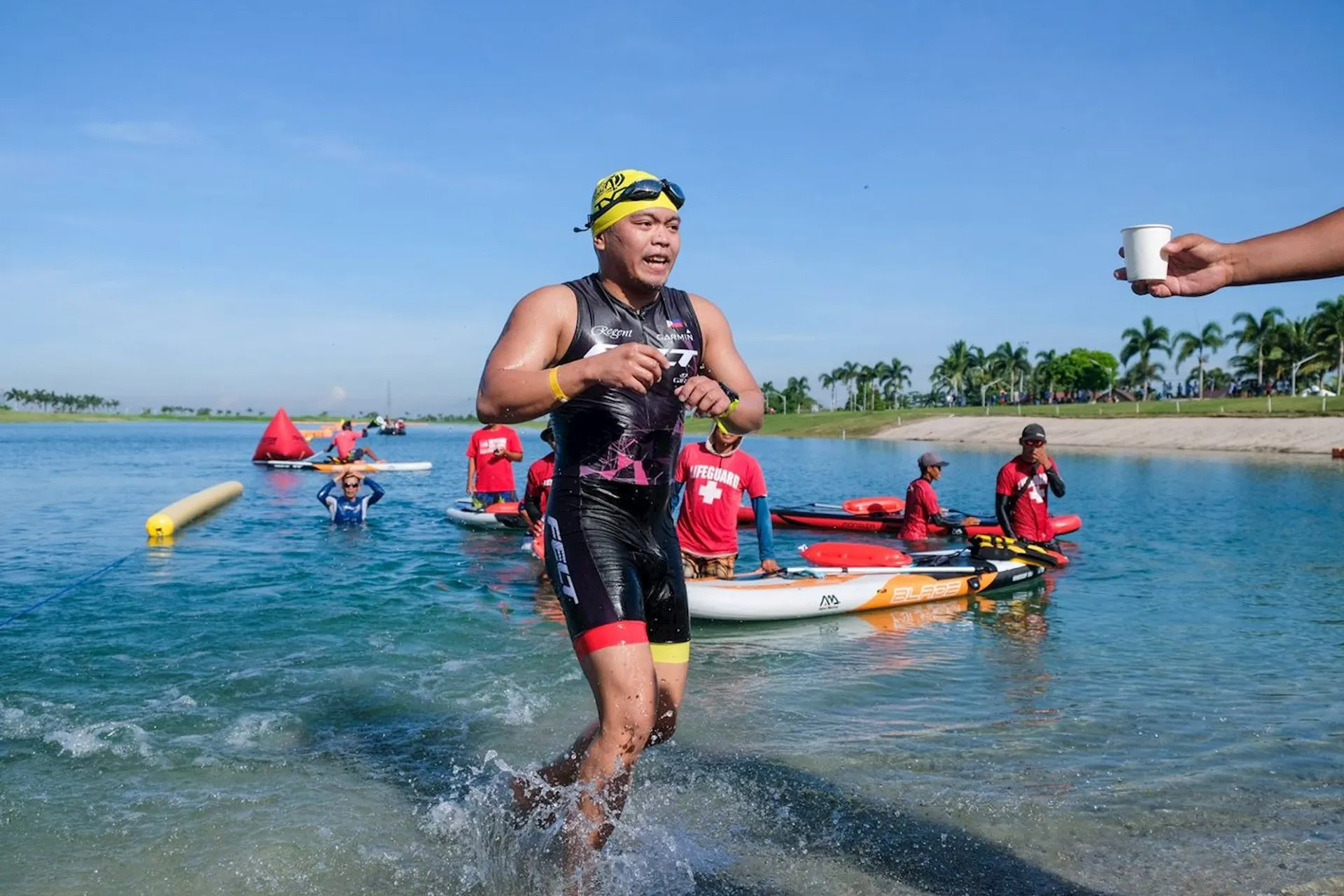 In the image, there's an athlete running out of the water during a tri