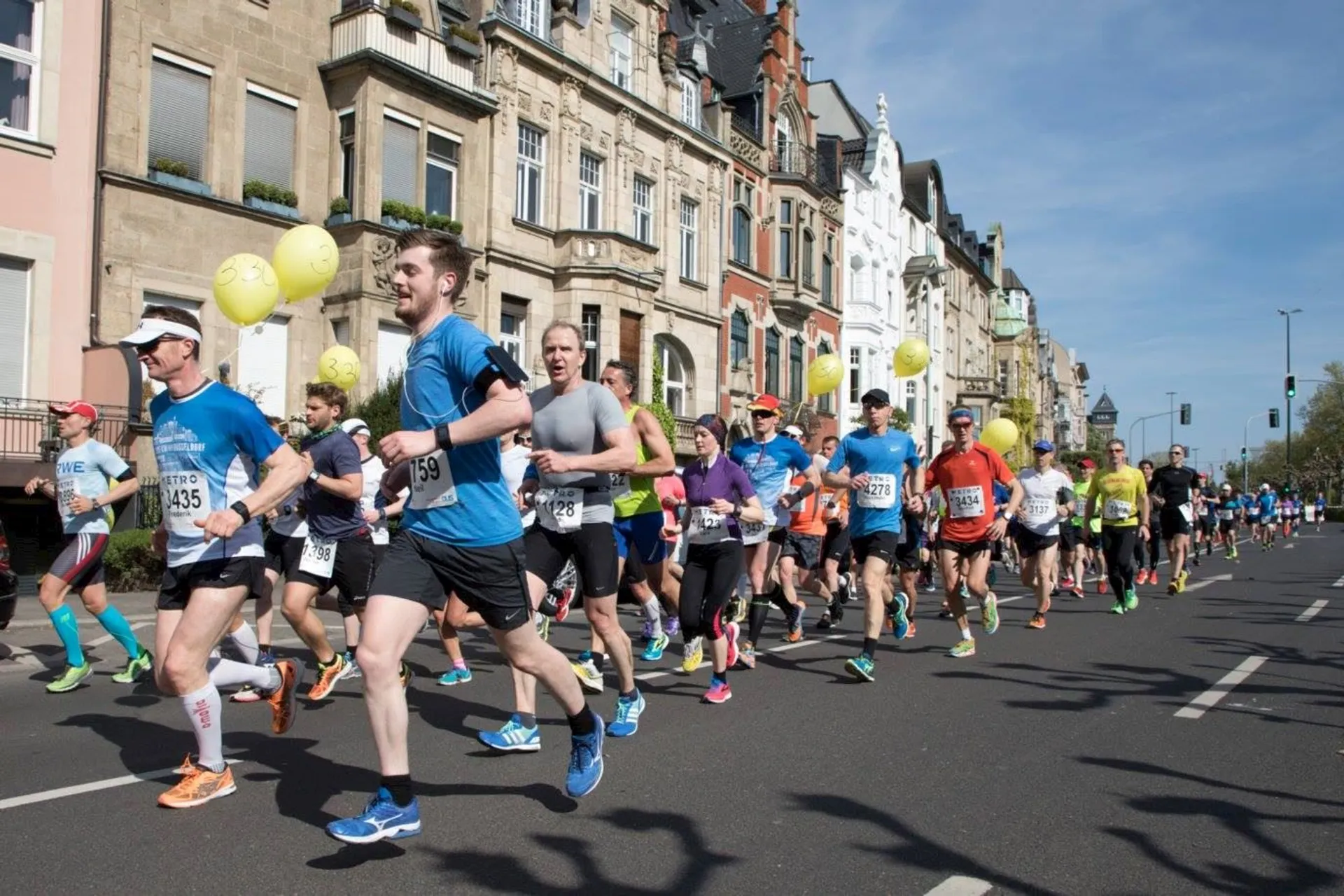 The image shows a group of people participating in a road race, likely a marathon