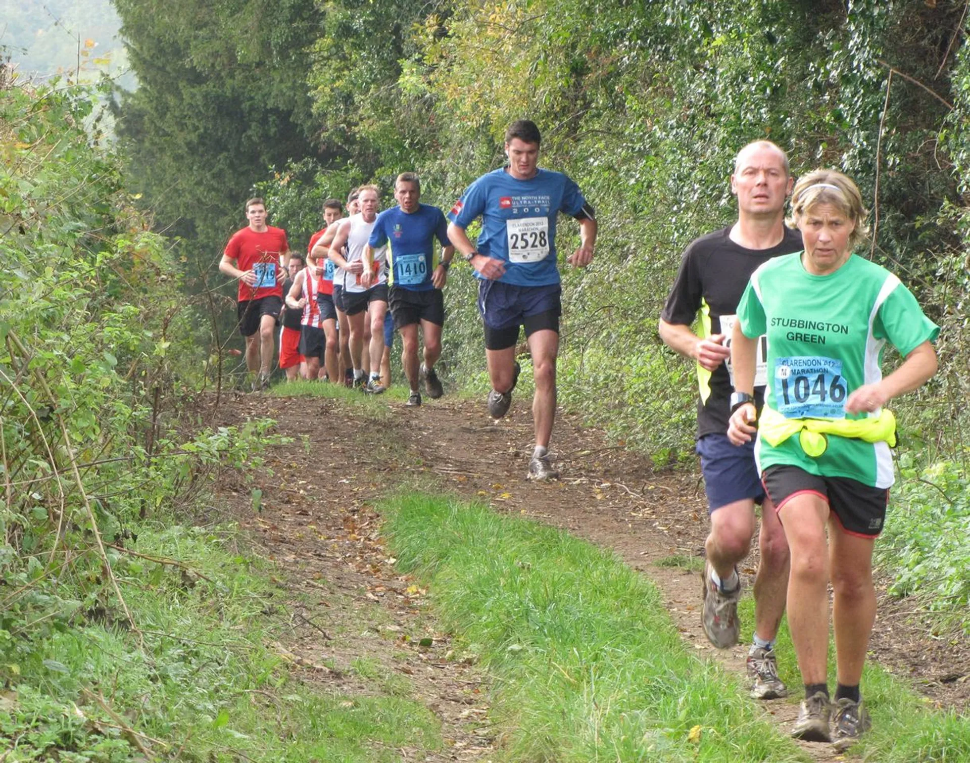 The image shows a group of runners participating in a cross country or trail running event