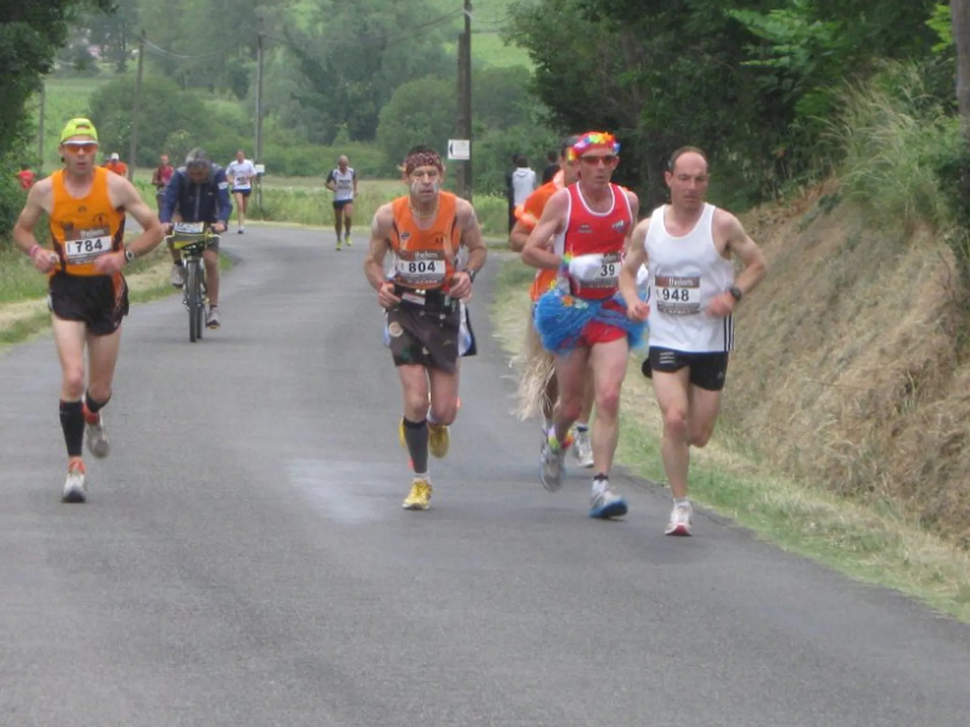 The image shows four people participating in a running event. They are running on a