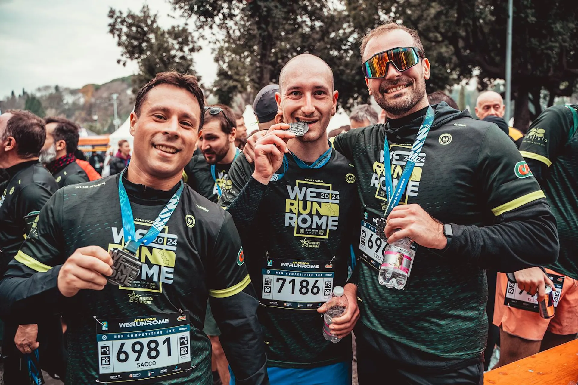 This image shows a group of people holding medals and smiling after completing a race. They are wearing matching athletic gear with "We Run Rome" written on it, and appear to be celebrating their achievement.