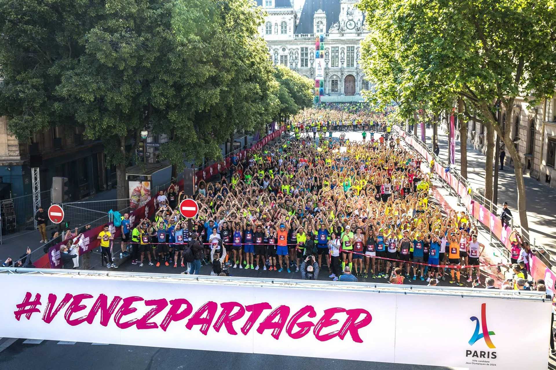 The image displays a large group of participants gathered for a running event, likely a