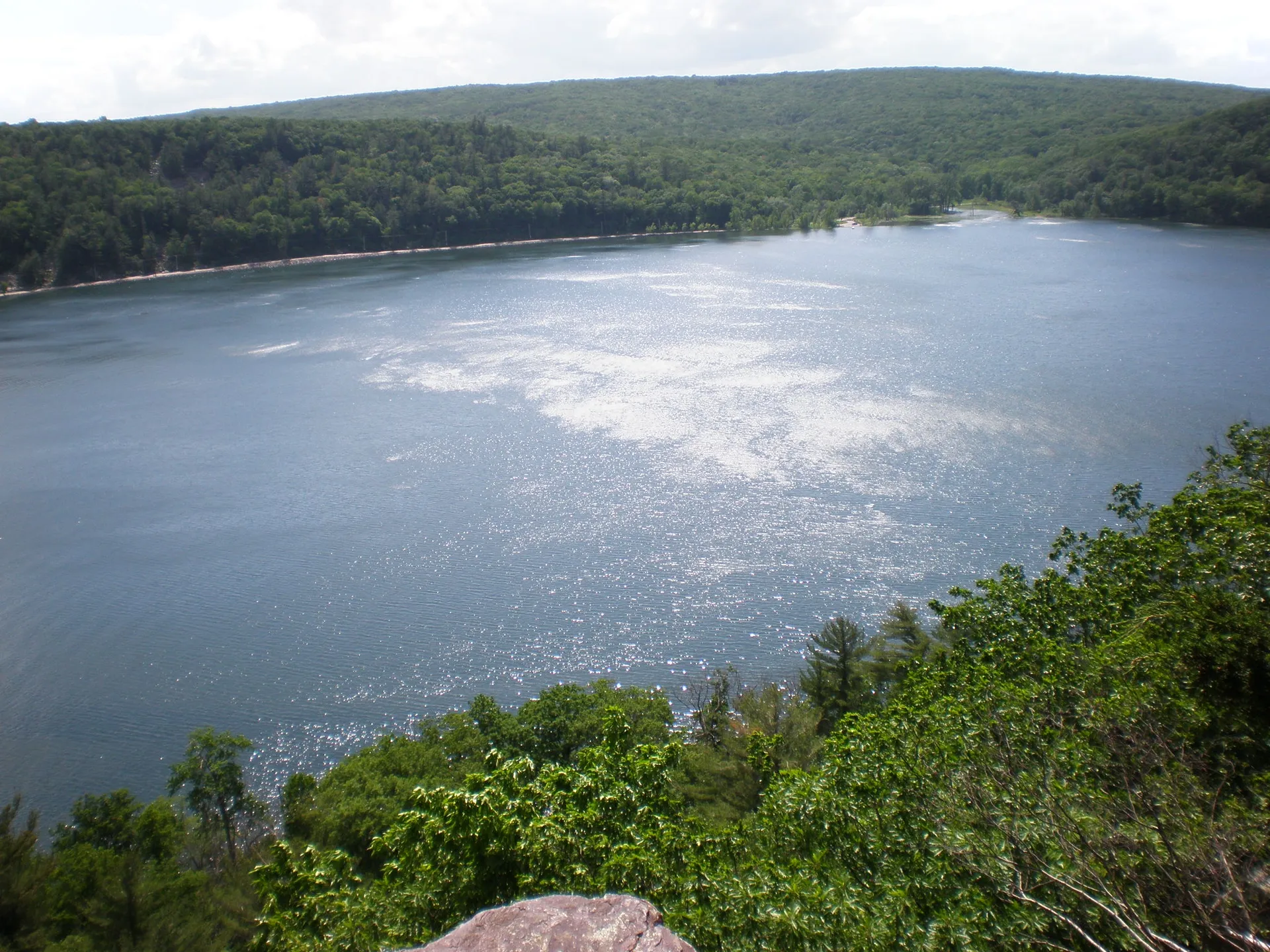 The image shows a scenic view of a lake surrounded by forested hills. The