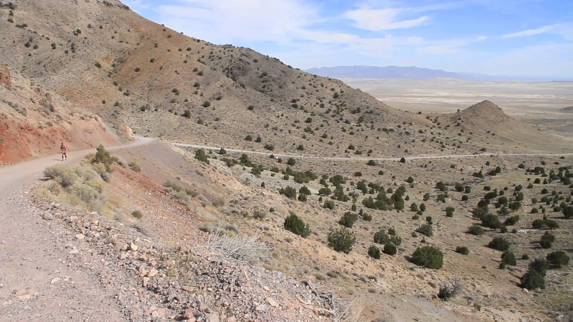 The image shows a semi-arid landscape with a winding road that cuts through rocky
