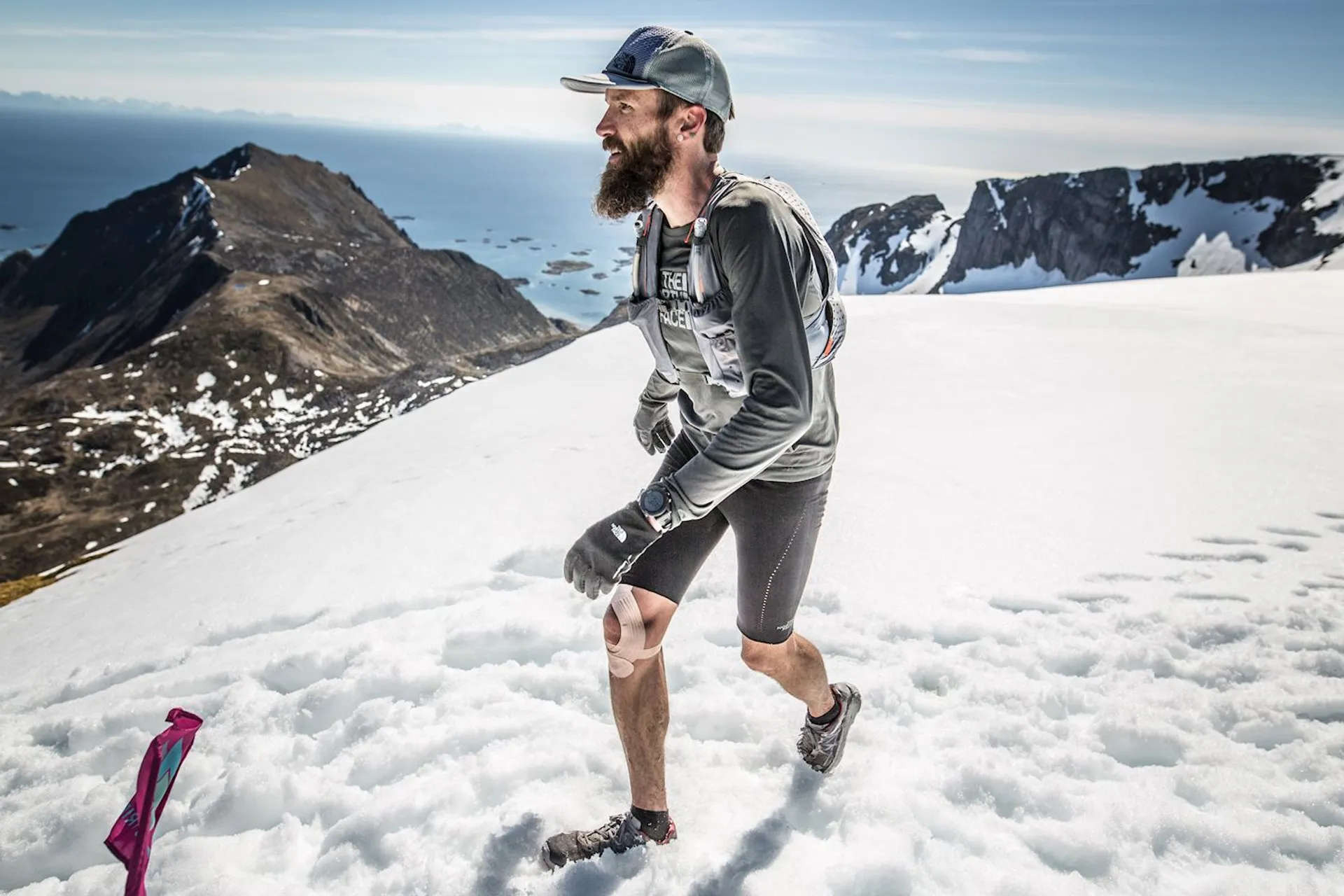 The image displays a man running through a snowy landscape with mountainous terrain in the