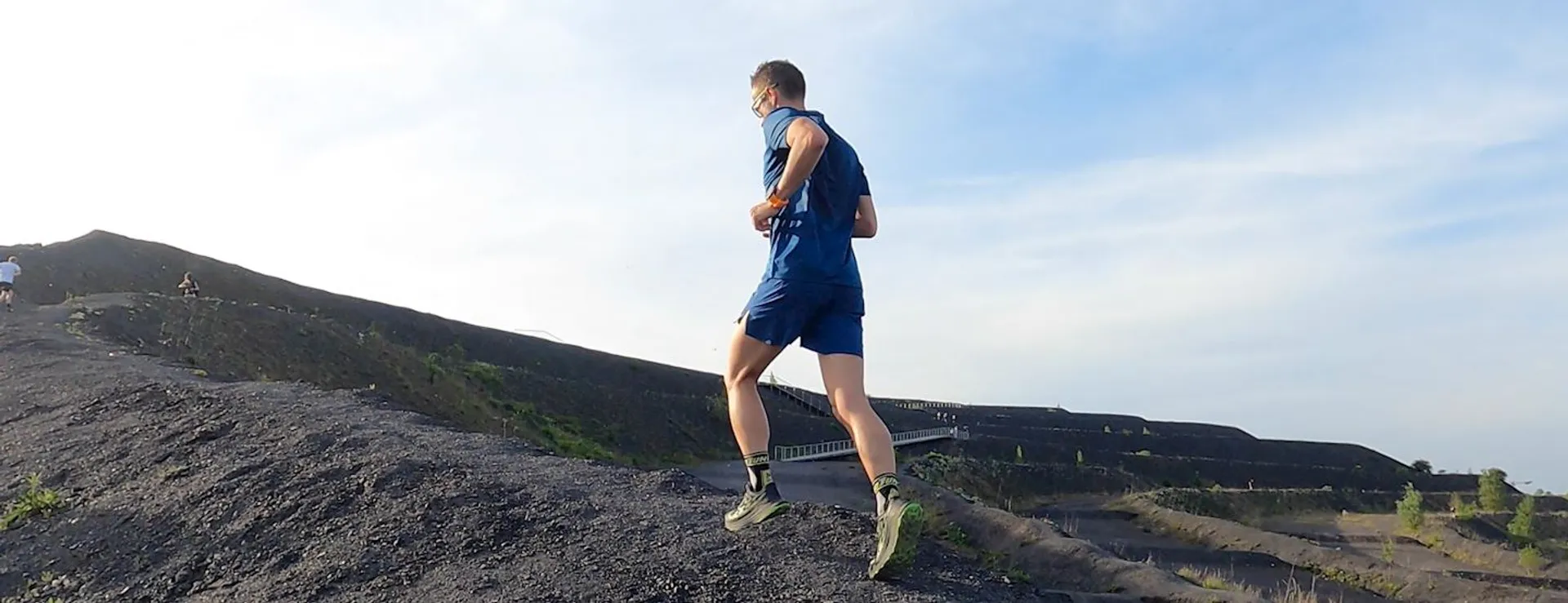 The image shows a person running outdoors on what appears to be a trail or path
