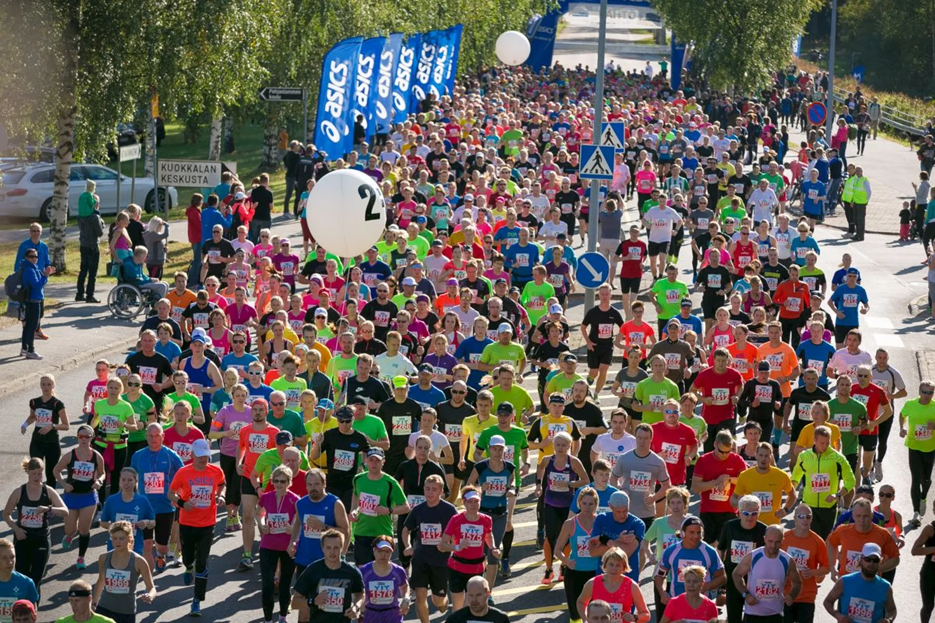 The image depicts a large group of people participating in a running event, such as