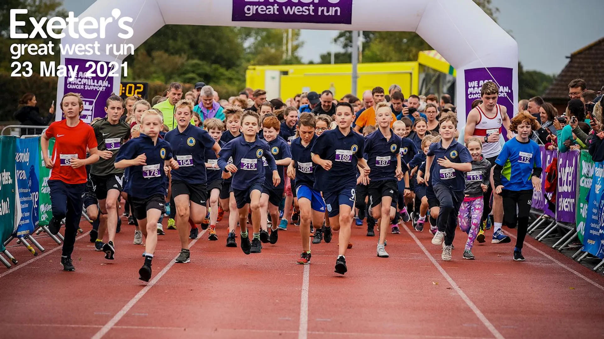 The image shows a group of young runners at the start line of a running event
