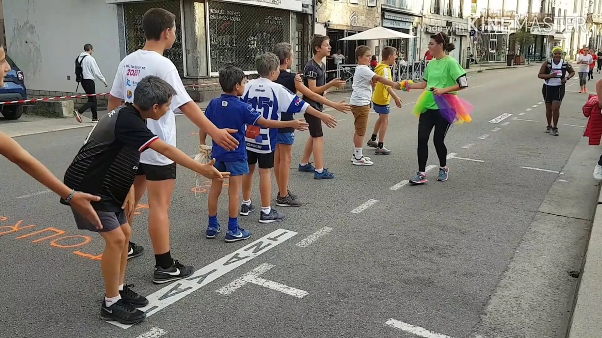 The image shows a street scene where a group of children and some adults are gathered