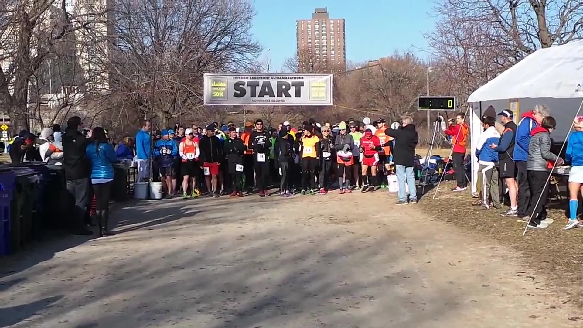 The image shows a group of runners lined up at the start line of a race