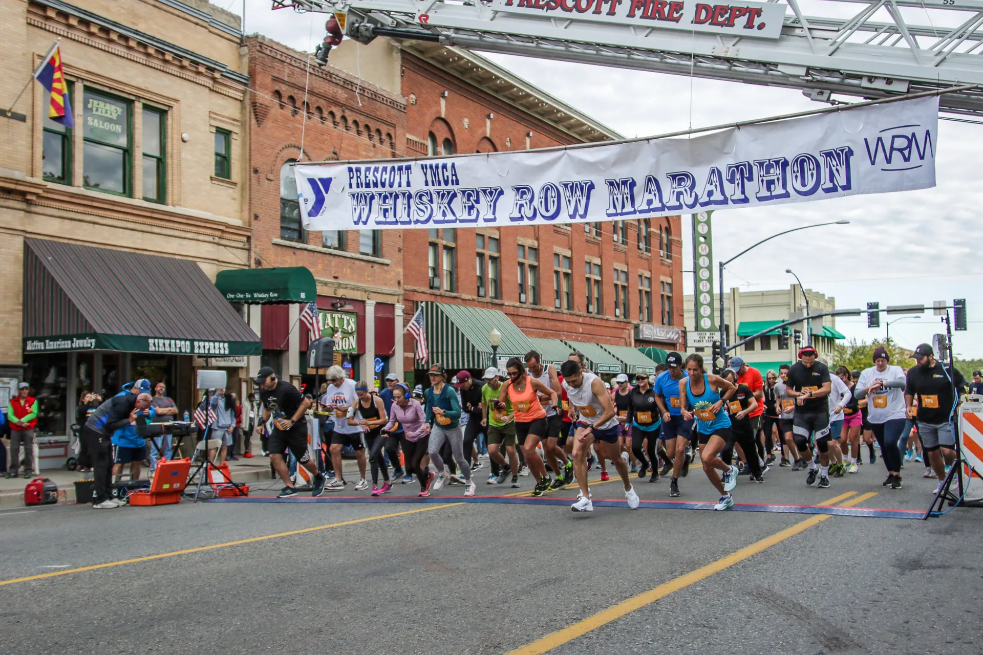 The image shows a group of runners at the start of a race, specifically the