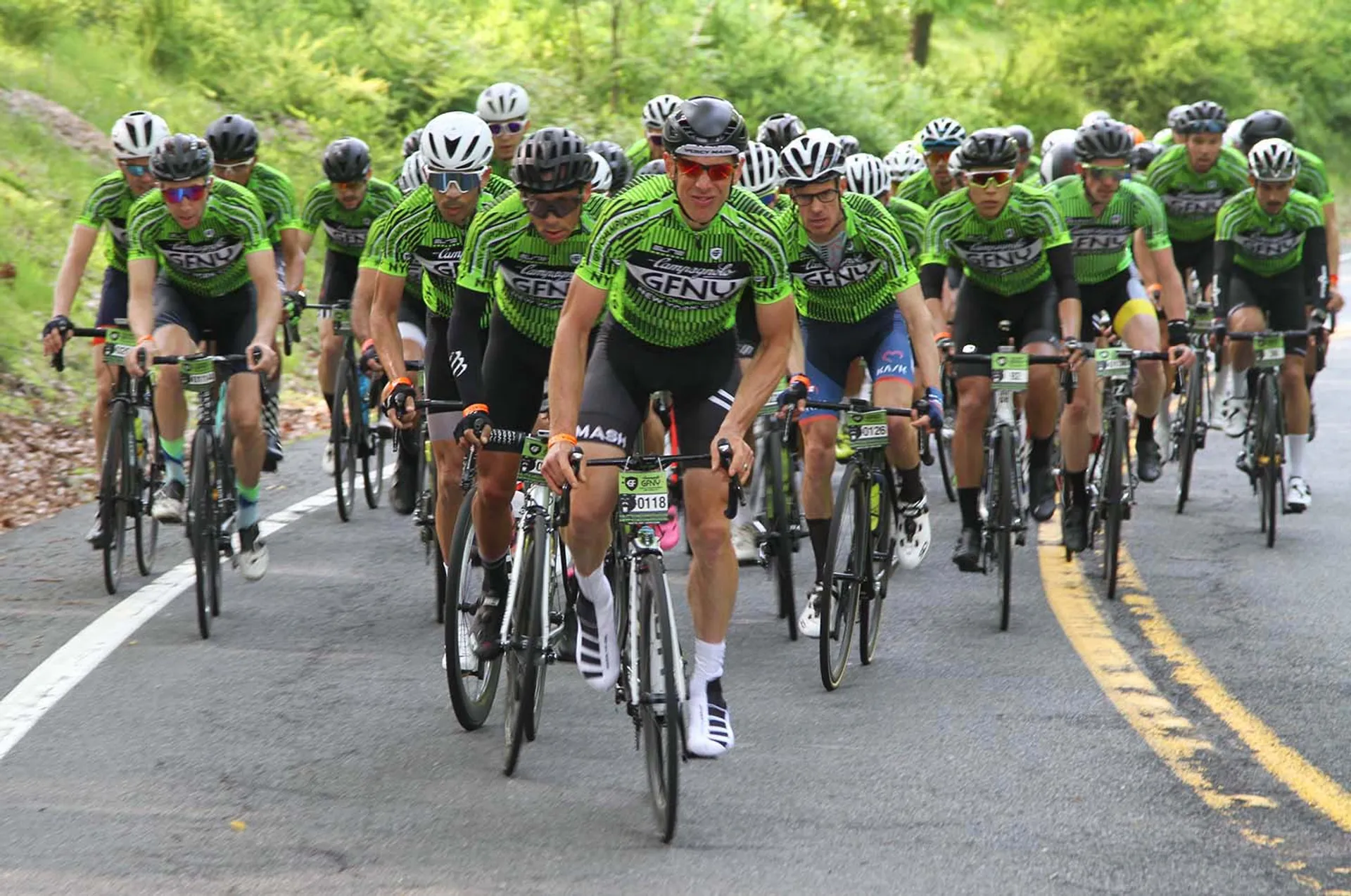 The image shows a group of cyclists dressed in matching cycling outfits, likely participating in