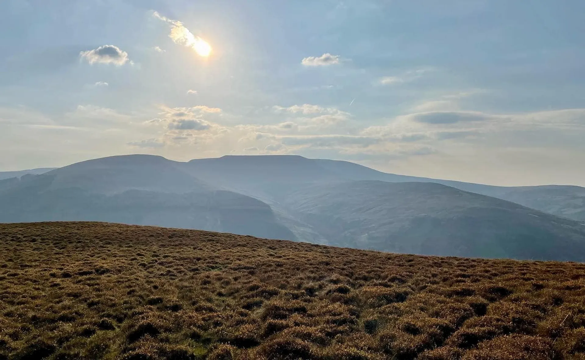 The image shows a scenic landscape with rolling hills and a view of mountainous terrain