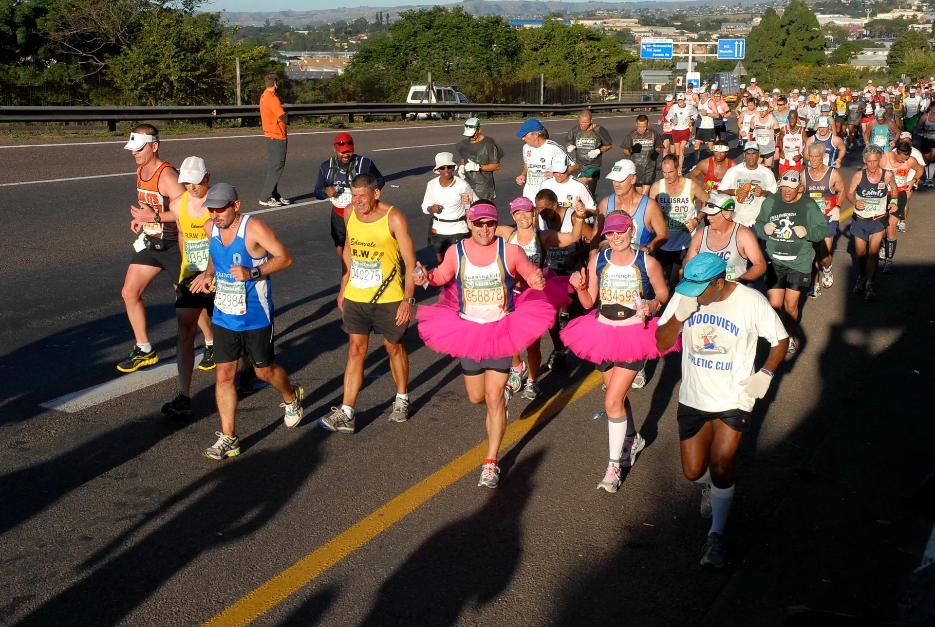 The image shows a large group of people participating in a running event or marathon.