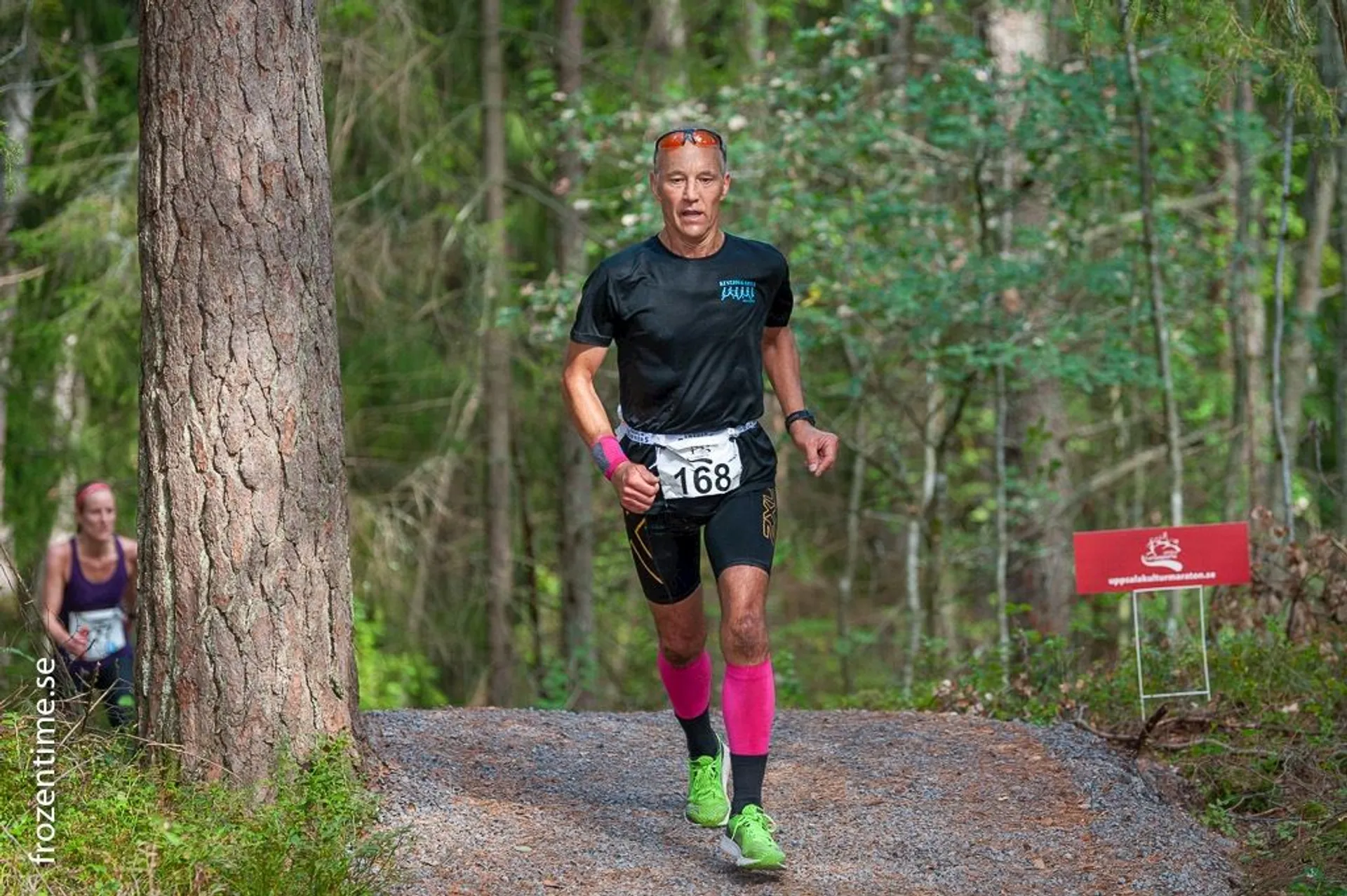 In the image, you see a person running a trail through a forested area