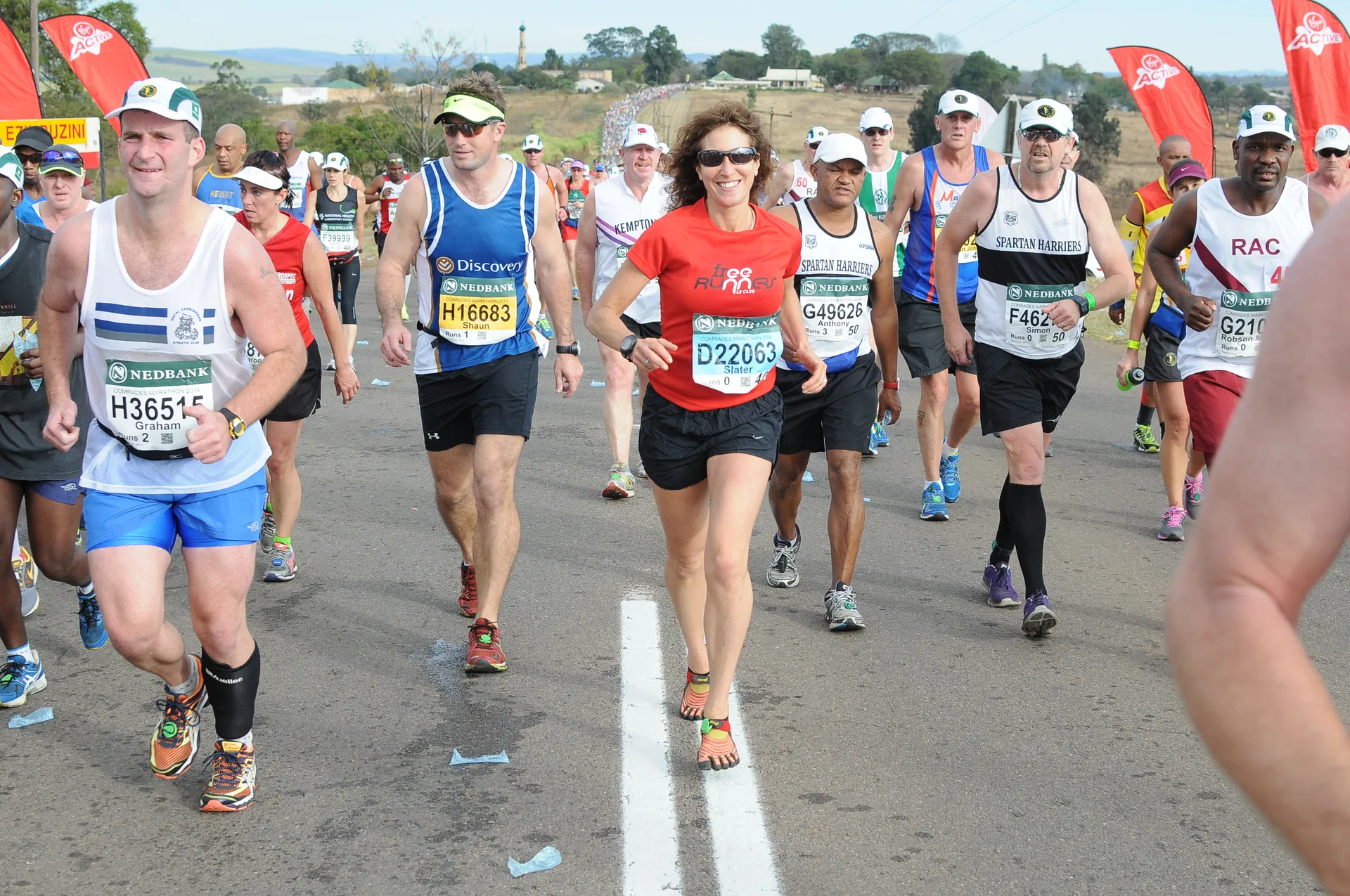 The image depicts a group of people participating in a road running event. They are