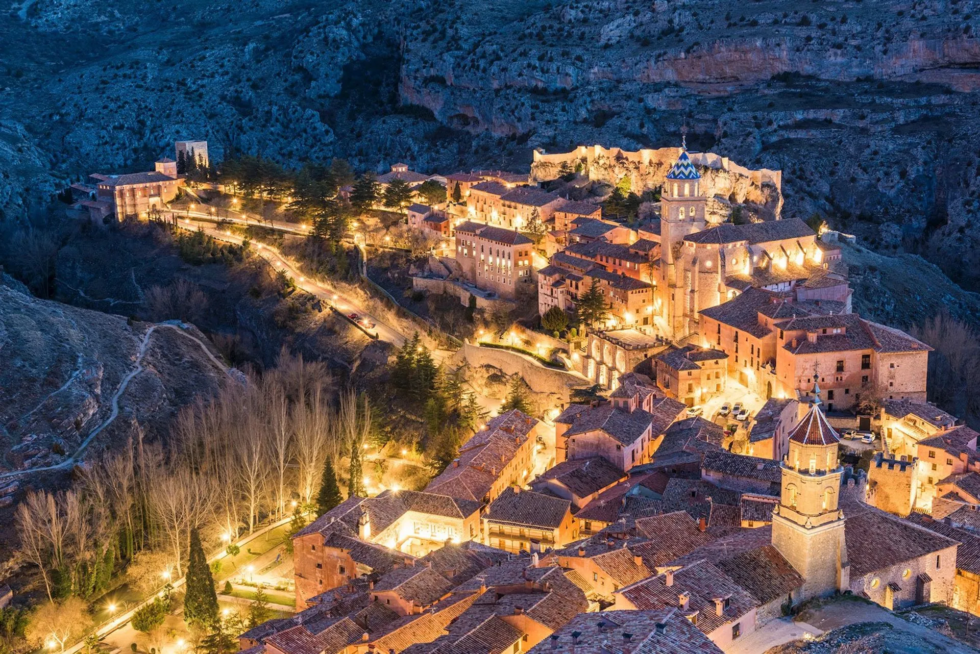 This image depicts a stunning evening view of an old town nestled within a mountainous