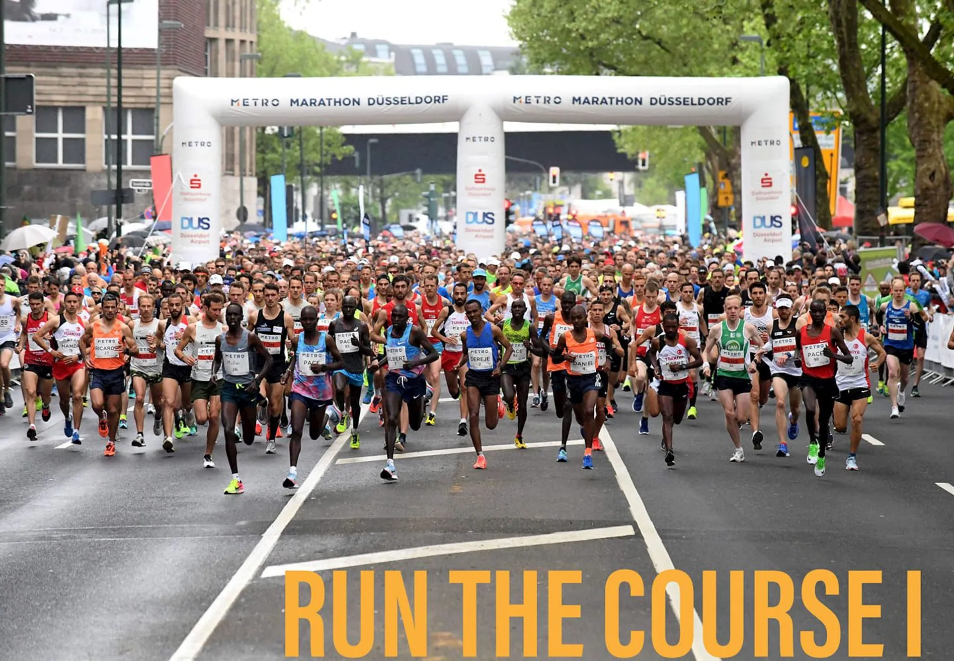 The image shows a large group of runners participating in a marathon. They are on
