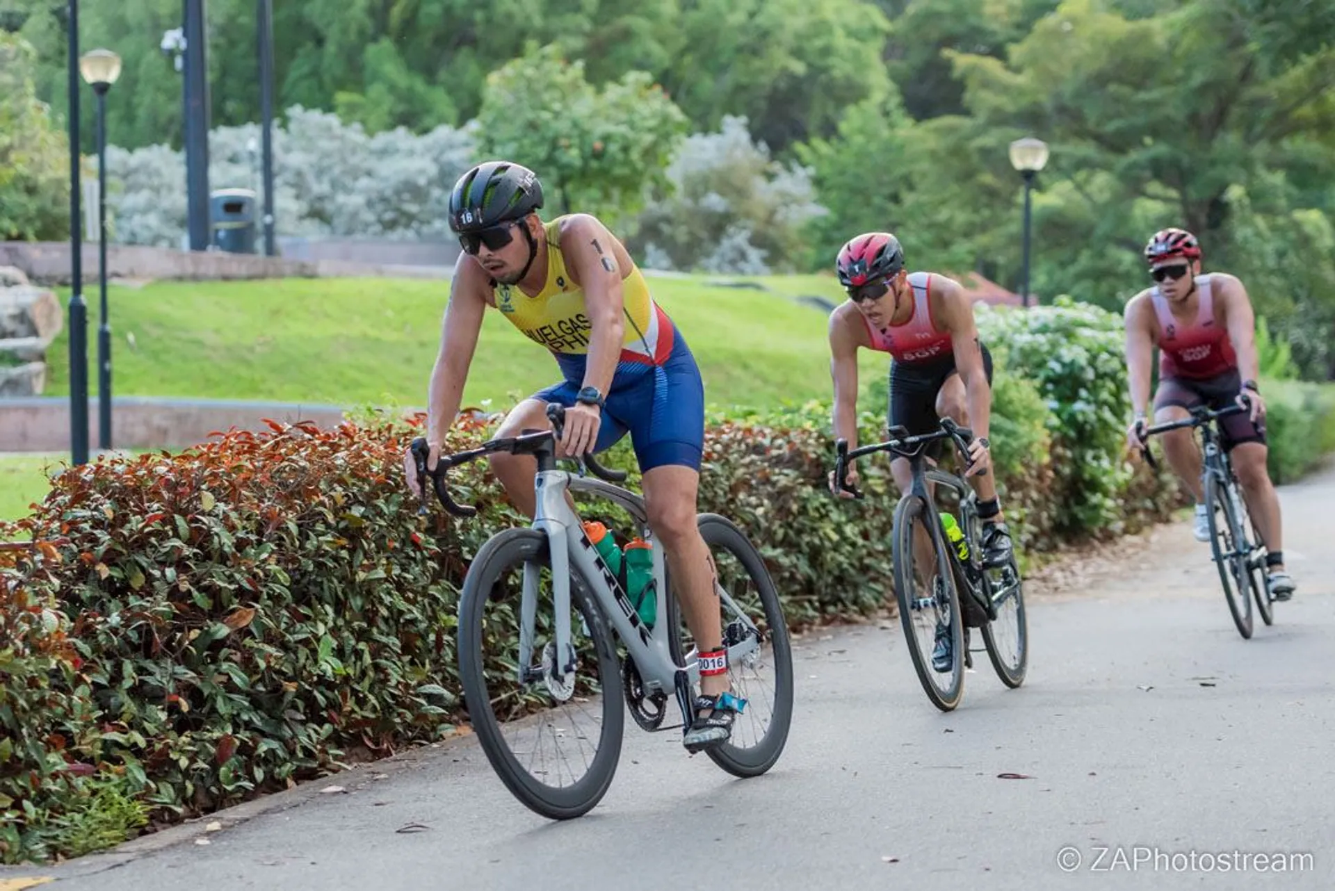 The image shows three individuals participating in a cycling event, likely part of a tri