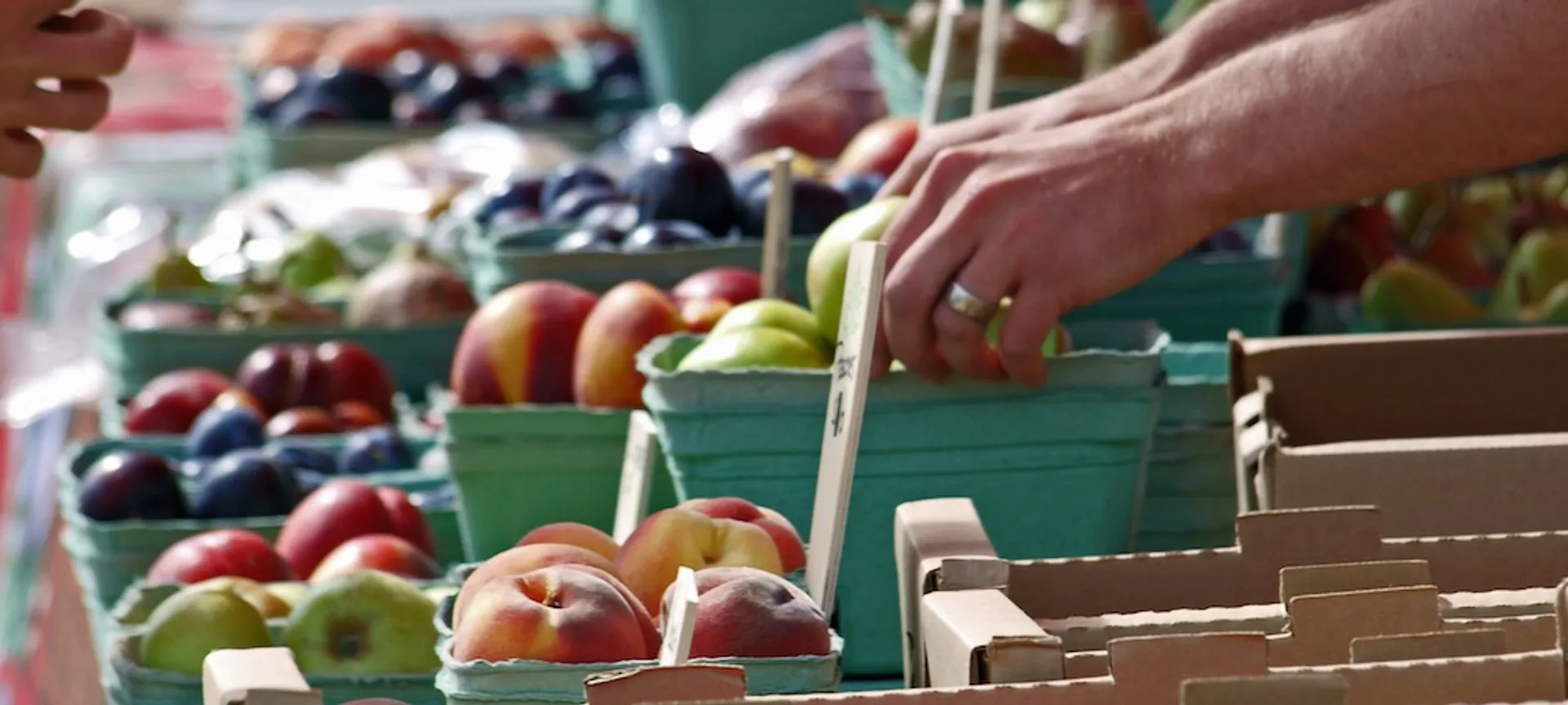 In this image, there are various fruits displayed in containers, likely at a market