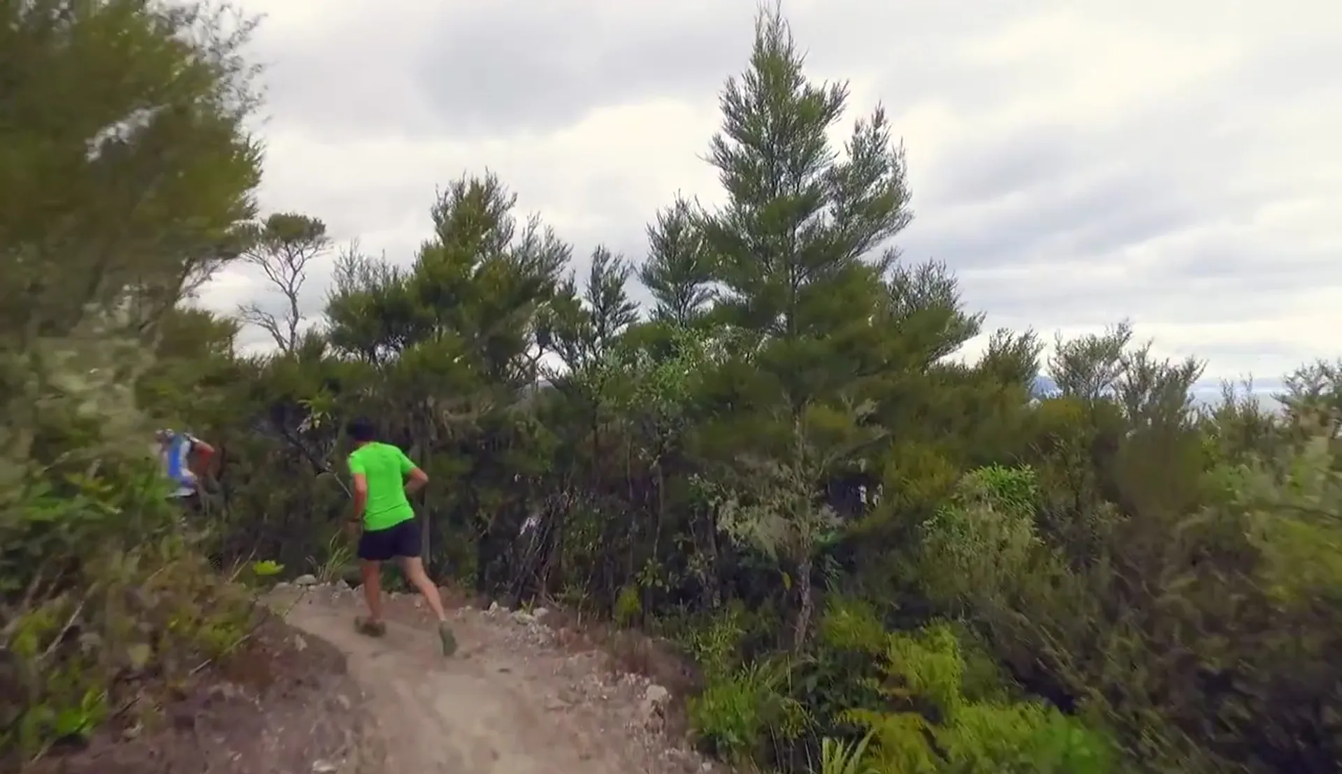 The image shows a person wearing a green top and black shorts, running or walking