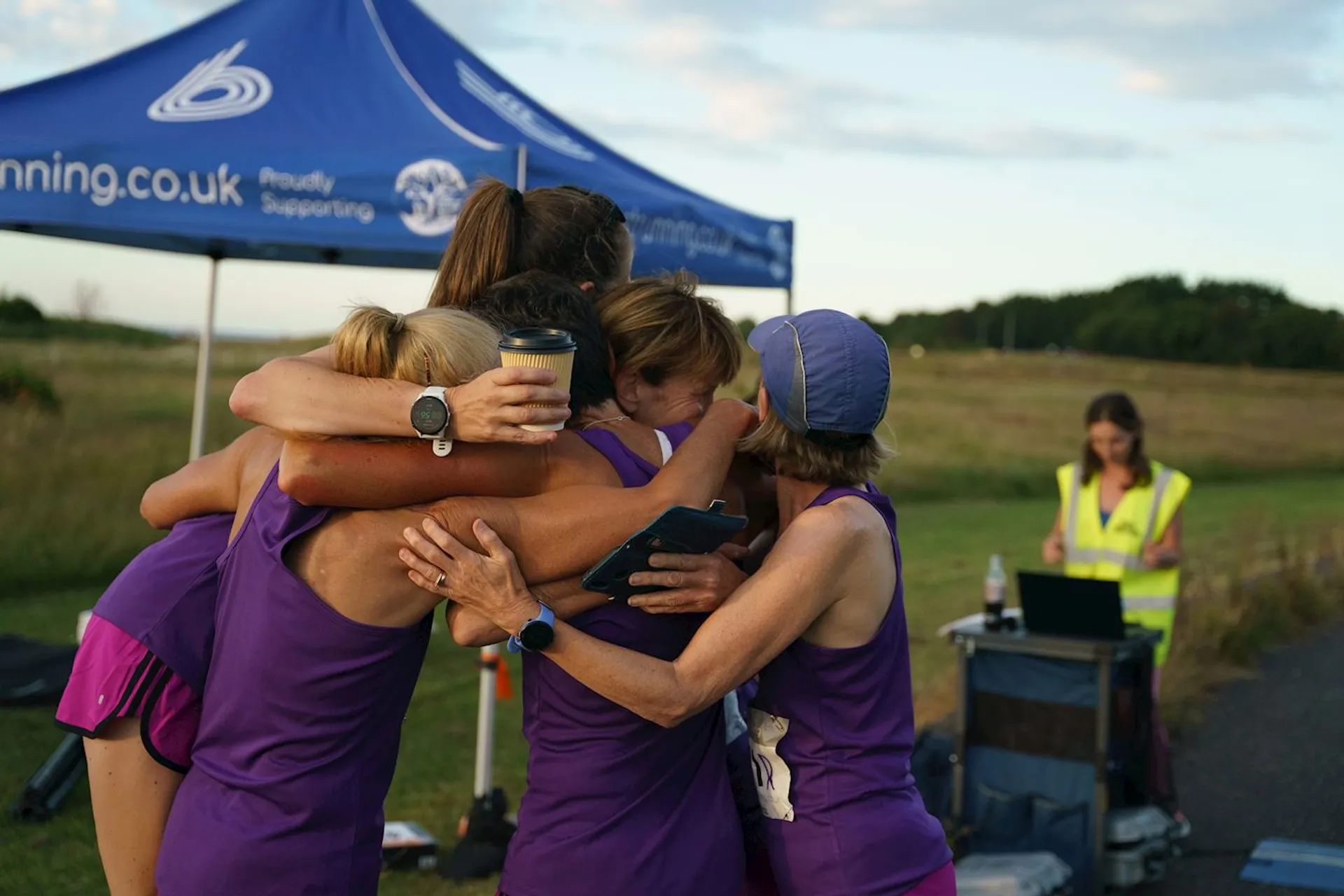 The image shows a group of people, likely runners, huddled together in a