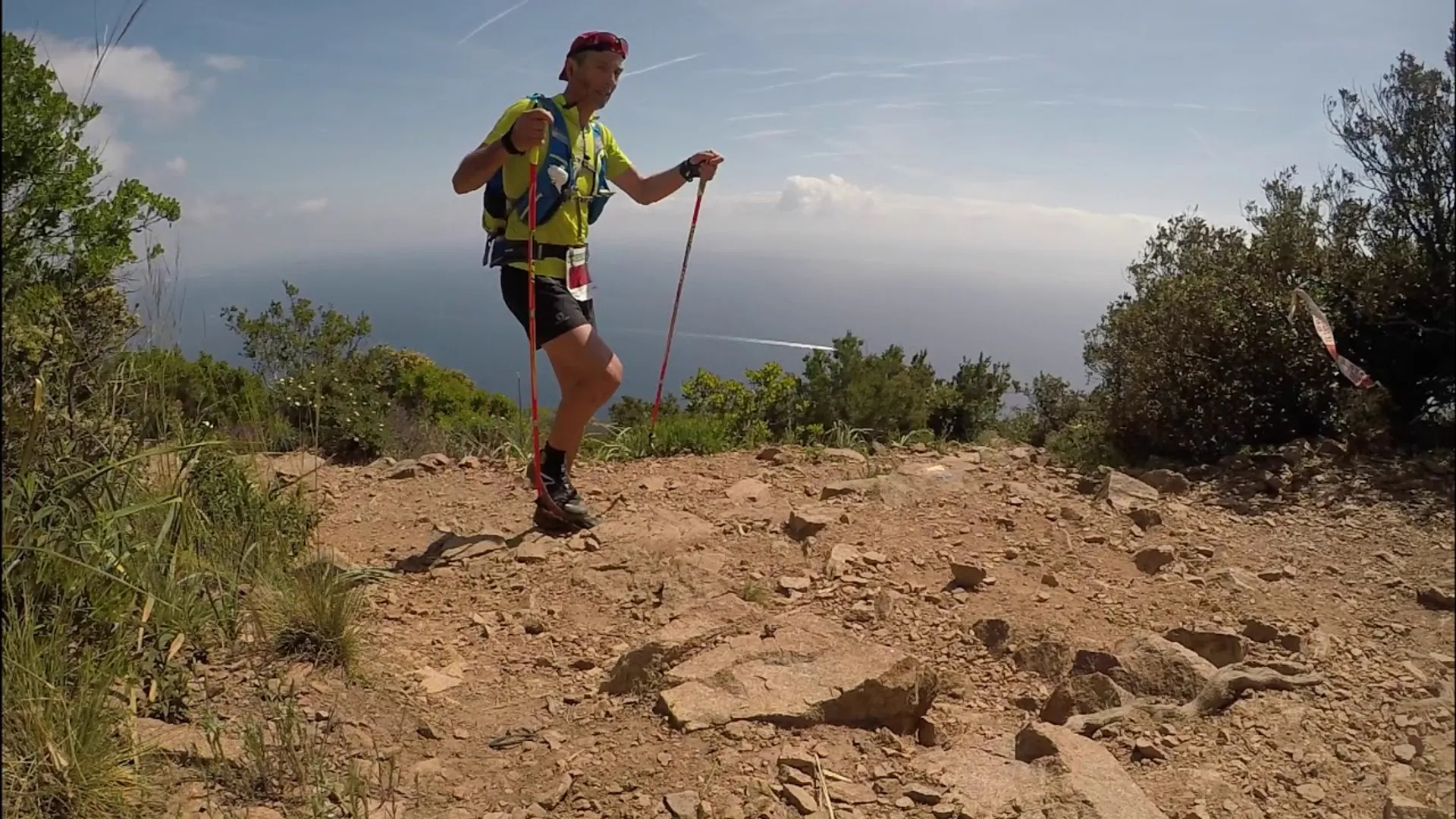 The image shows a person trail running in a natural outdoor setting. The individual is