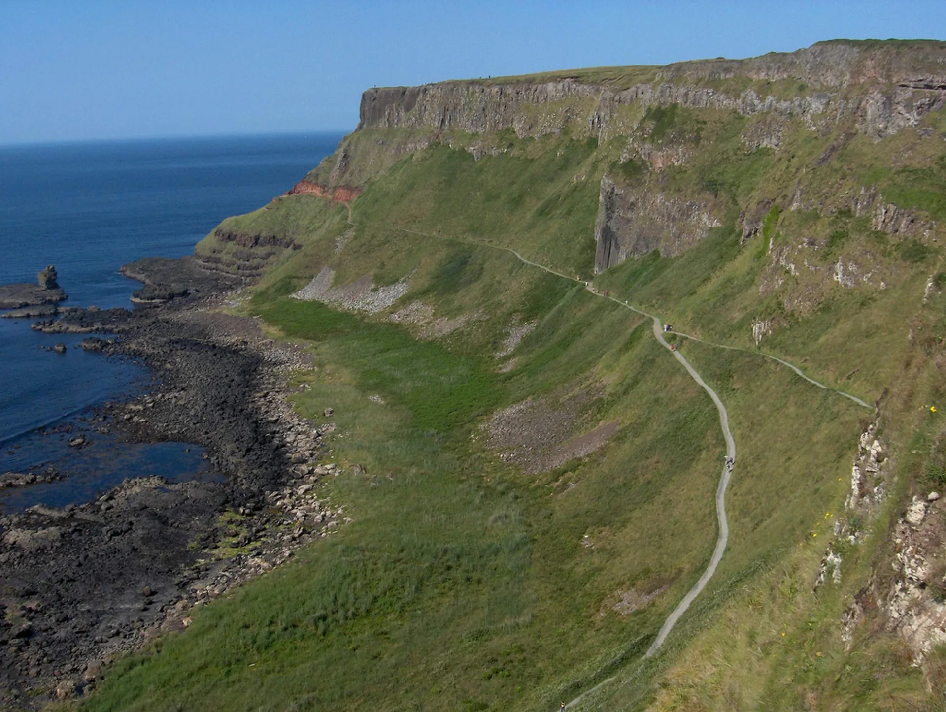 The image shows a coastal landscape with a prominent cliff face on the right side,