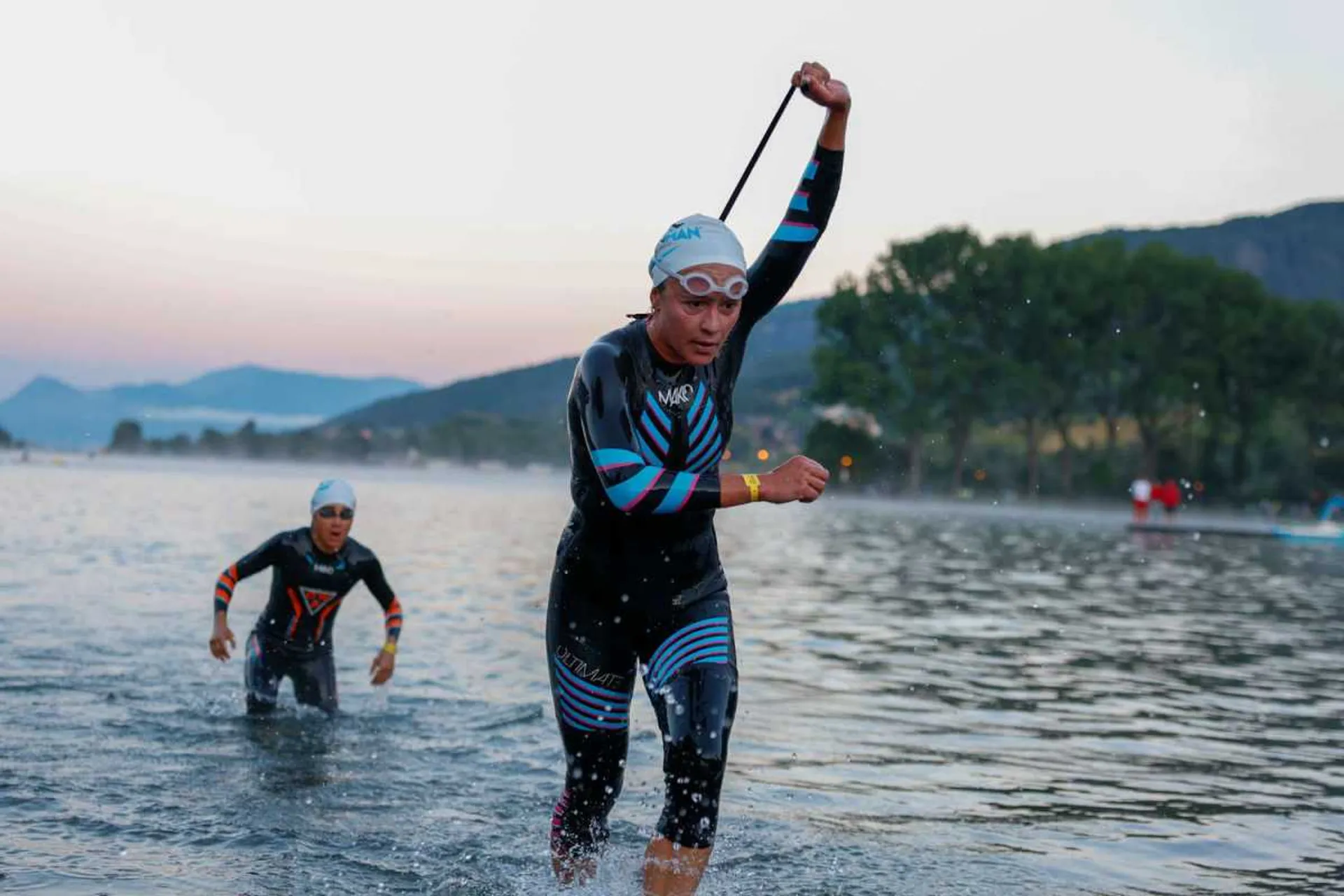 The image shows two individuals participating in a triathlon or open water swimming event.