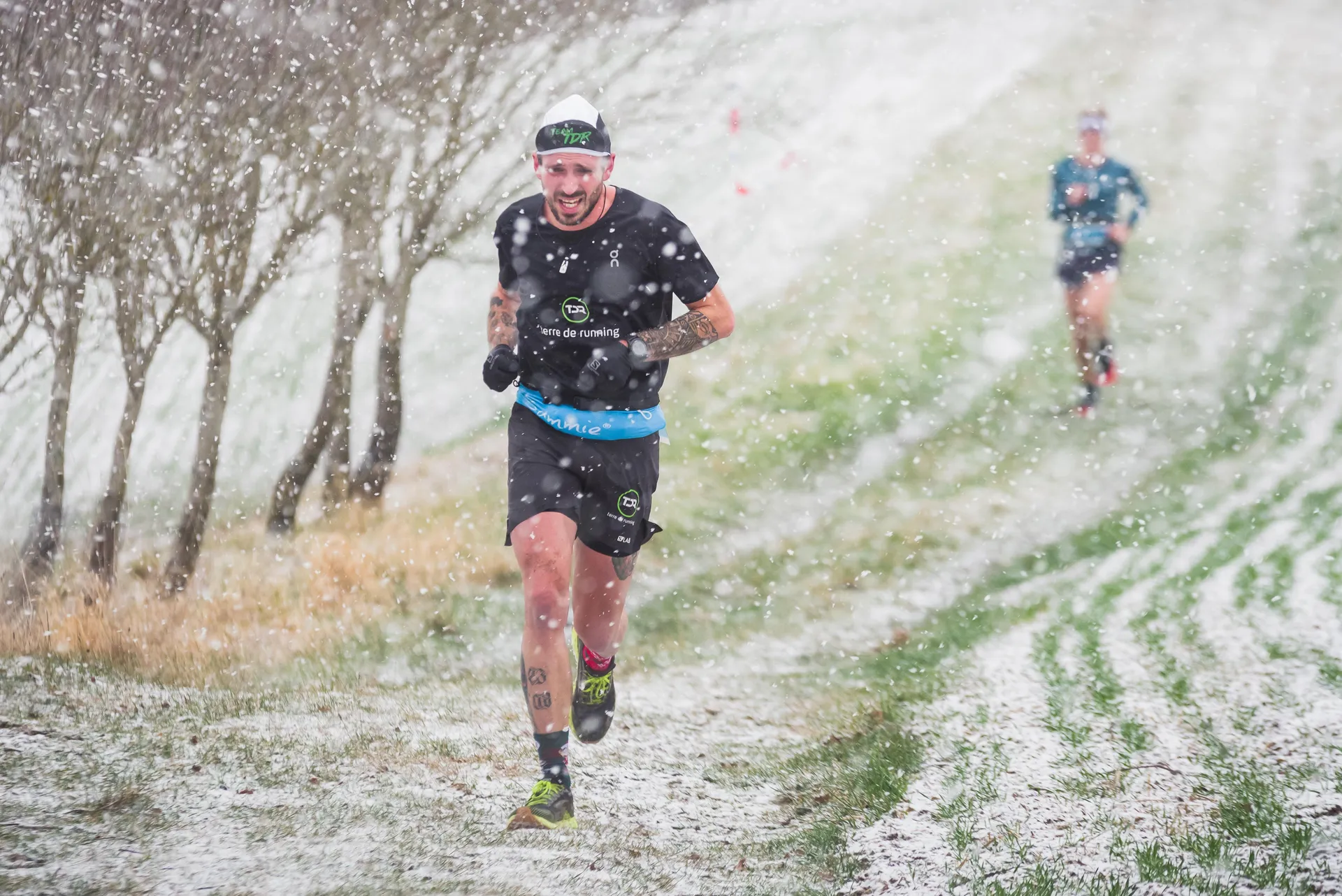 The image shows two individuals running outdoors during what appears to be snowy weather. The