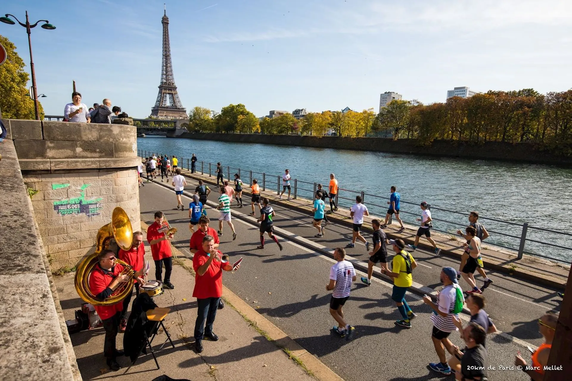 The image shows a group of runners participating in a marathon or race along a rivers