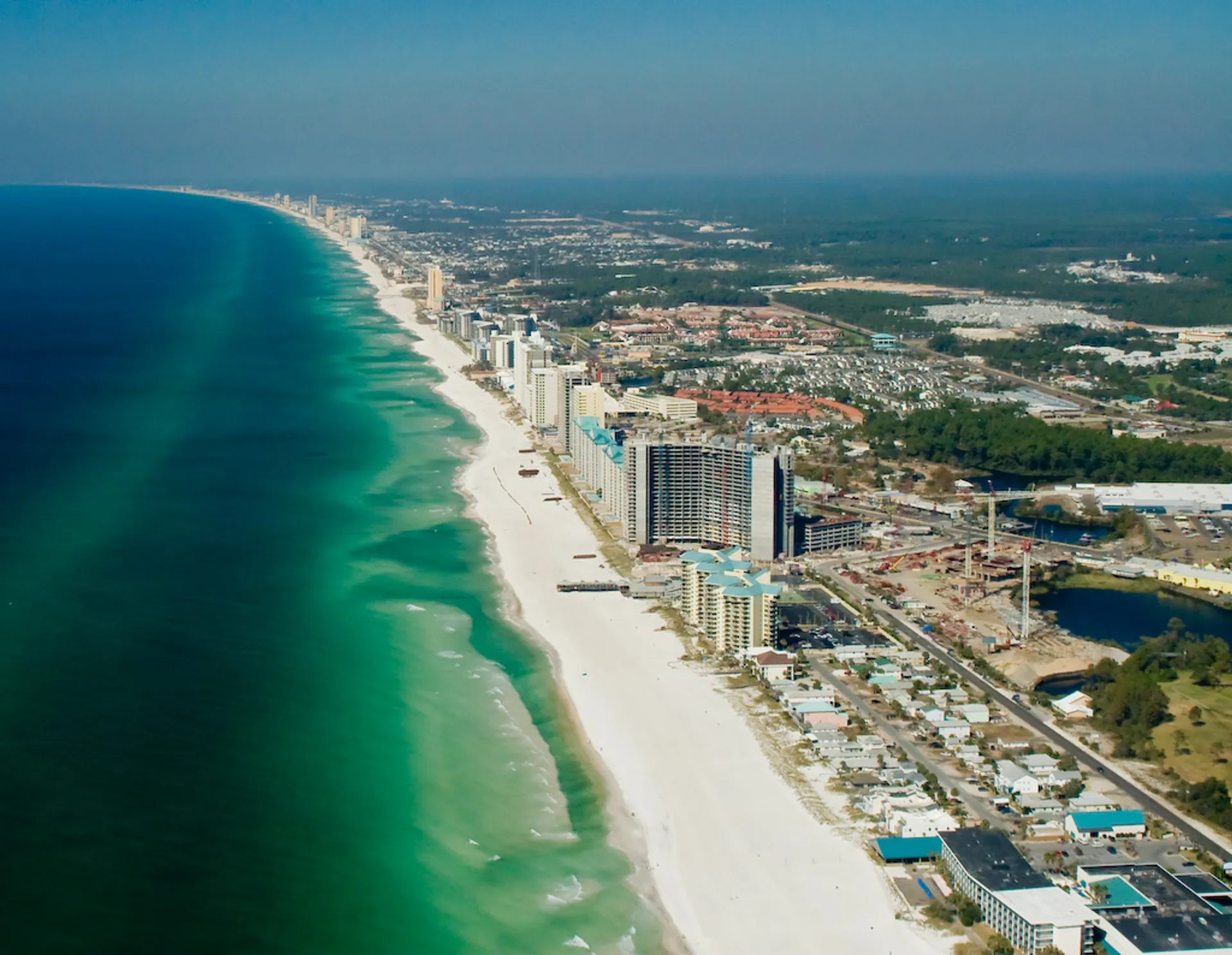 The image shows an aerial view of a coastal region with a long stretch of sandy