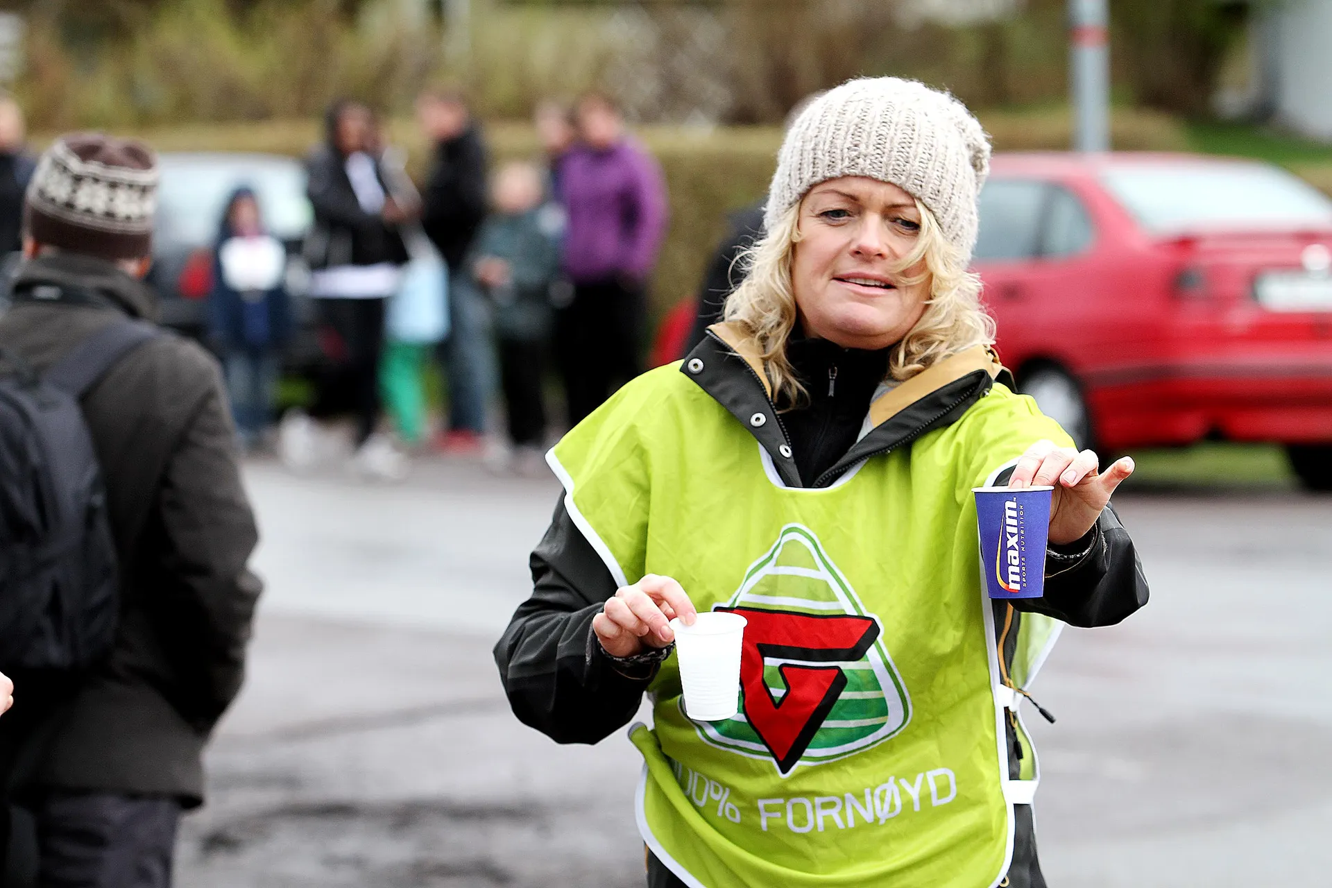 The image shows a person outdoors wearing a bright green vest with reflective stripes and a