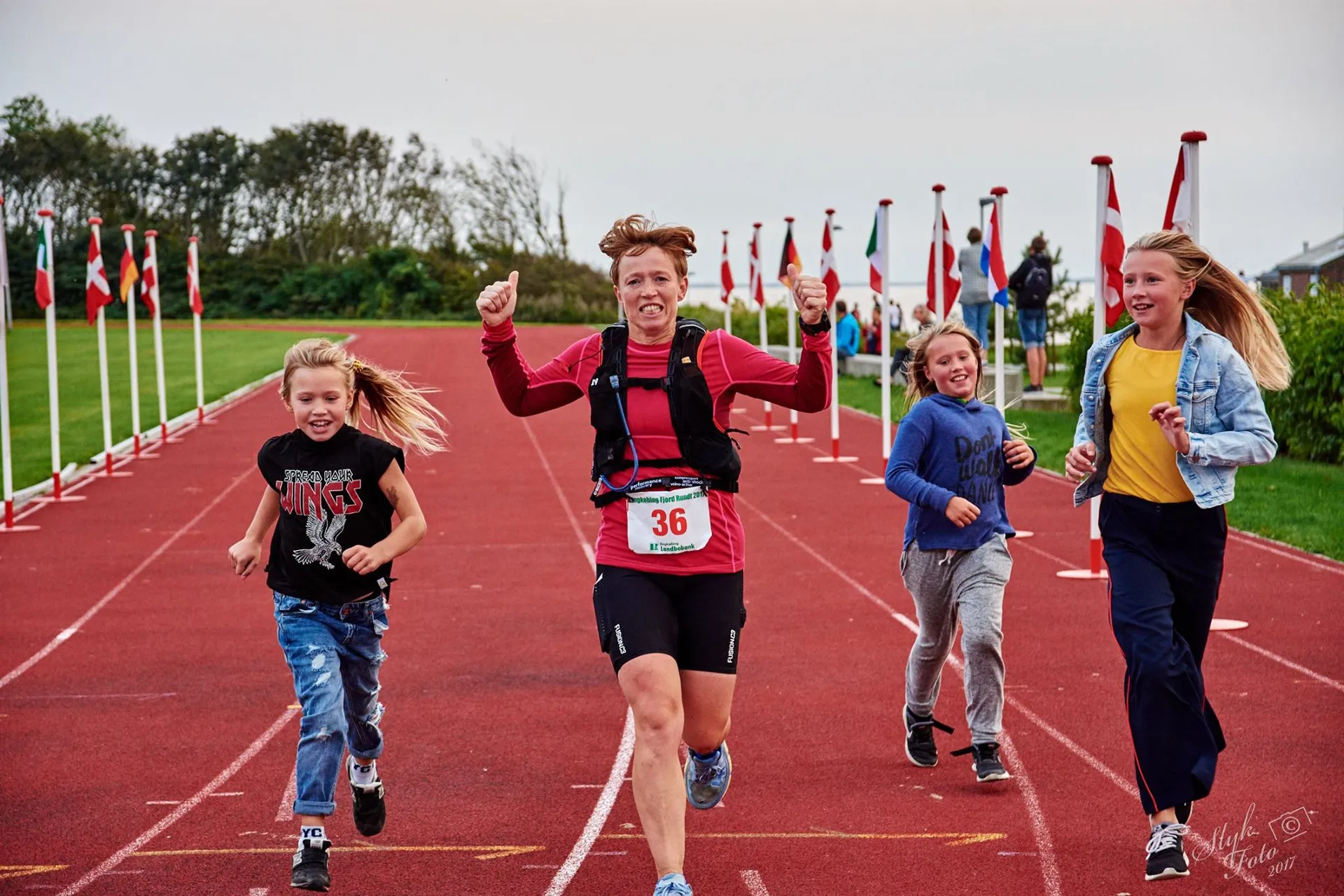 The image shows four people, likely a family, participating in a running event on