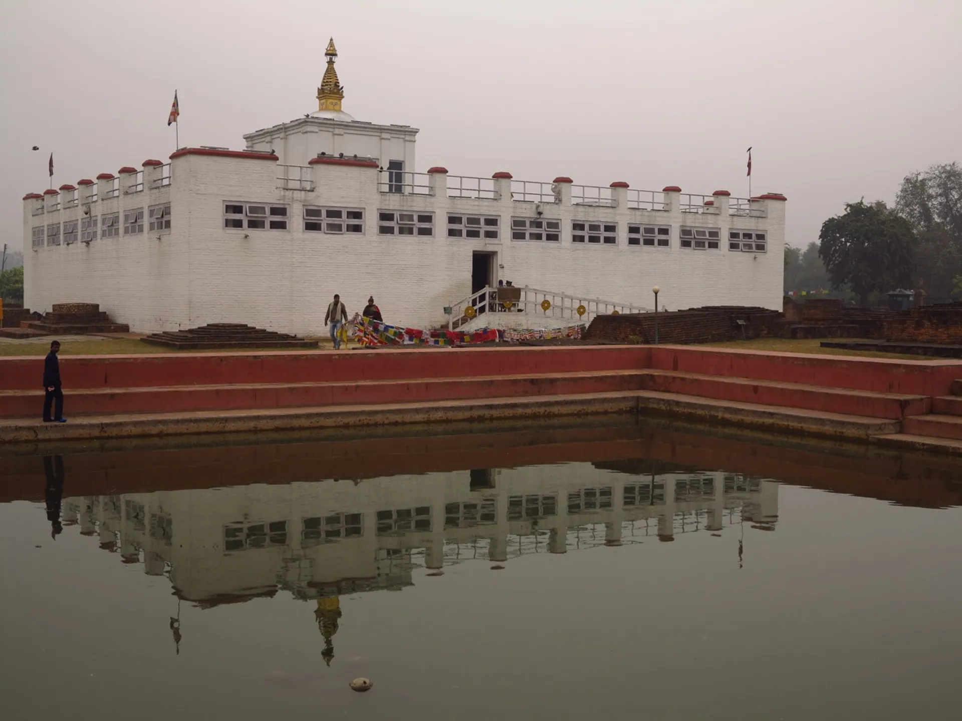 The image shows a white building with what appears to be traditional and possibly Buddhist architectural