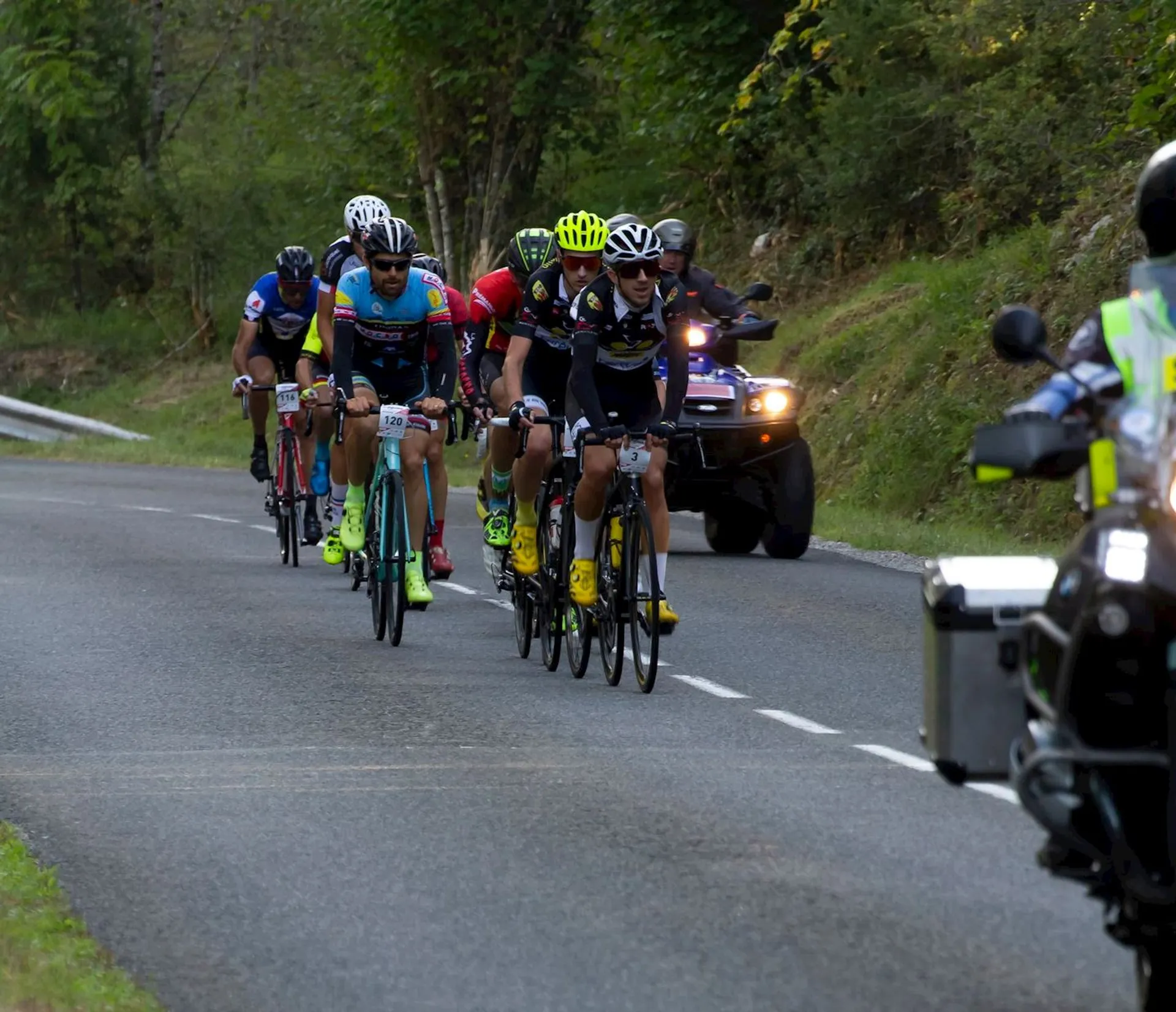 The image depicts a group of cyclists in a road race or cycling event. They
