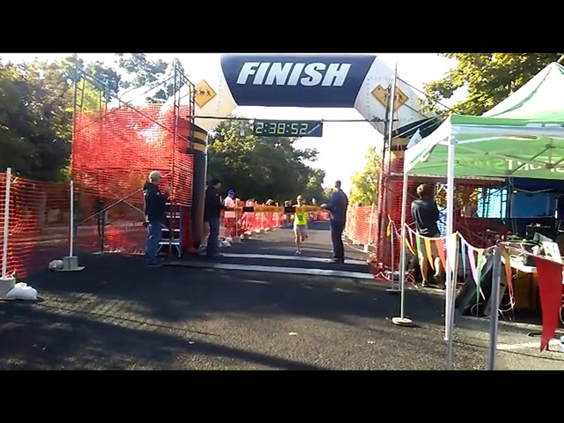 The image shows a running event with participants nearing the finish line. There's a