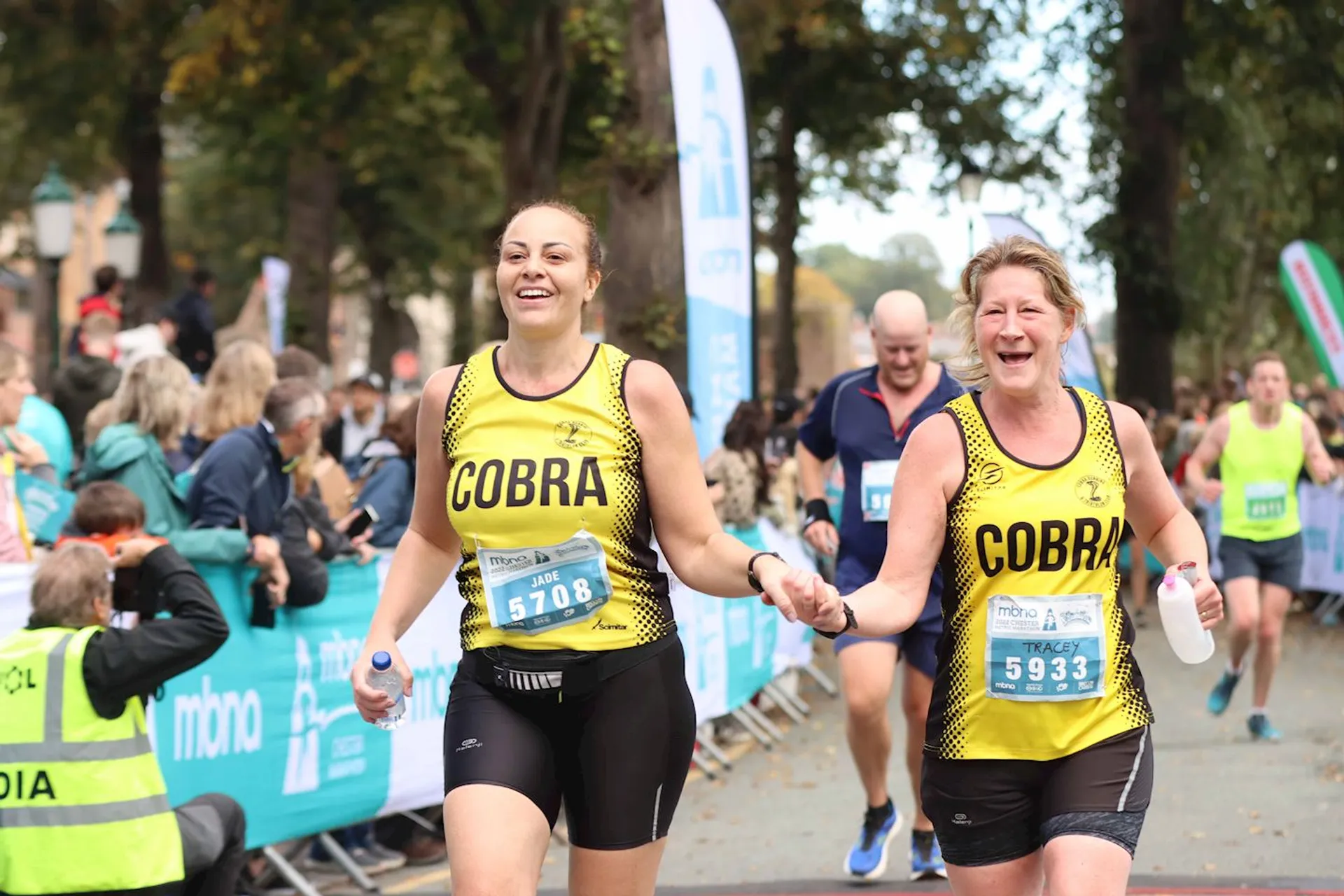 The image shows two participants in a running event, most likely a marathon or a