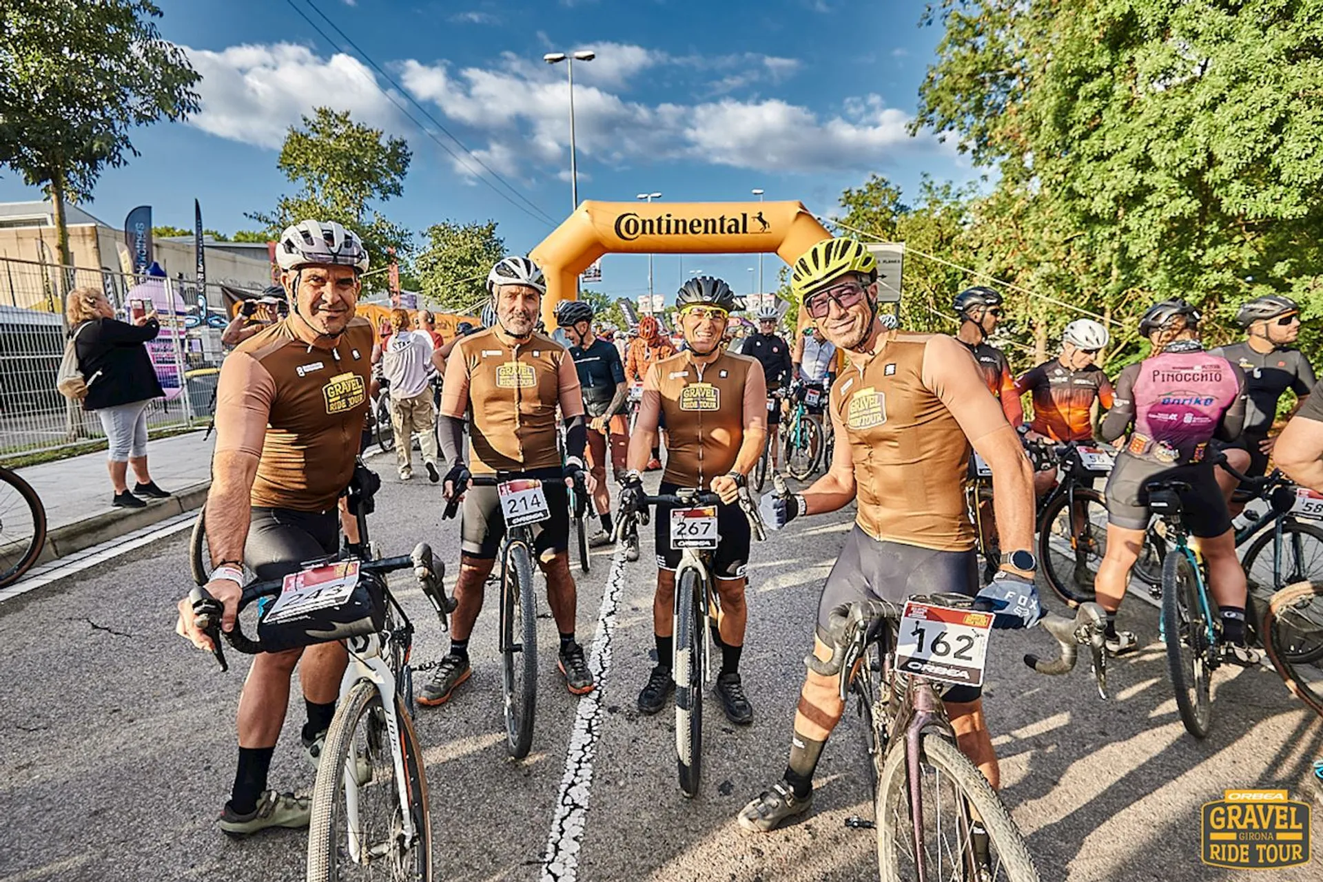 The image depicts a group of cyclists at a cycling event. They are wearing matching