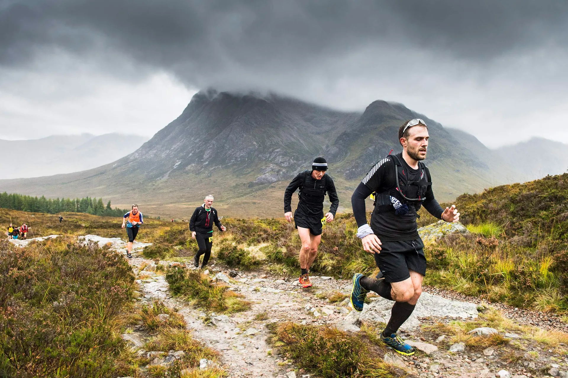 The image shows a group of people engaged in a trail run or a mountain running