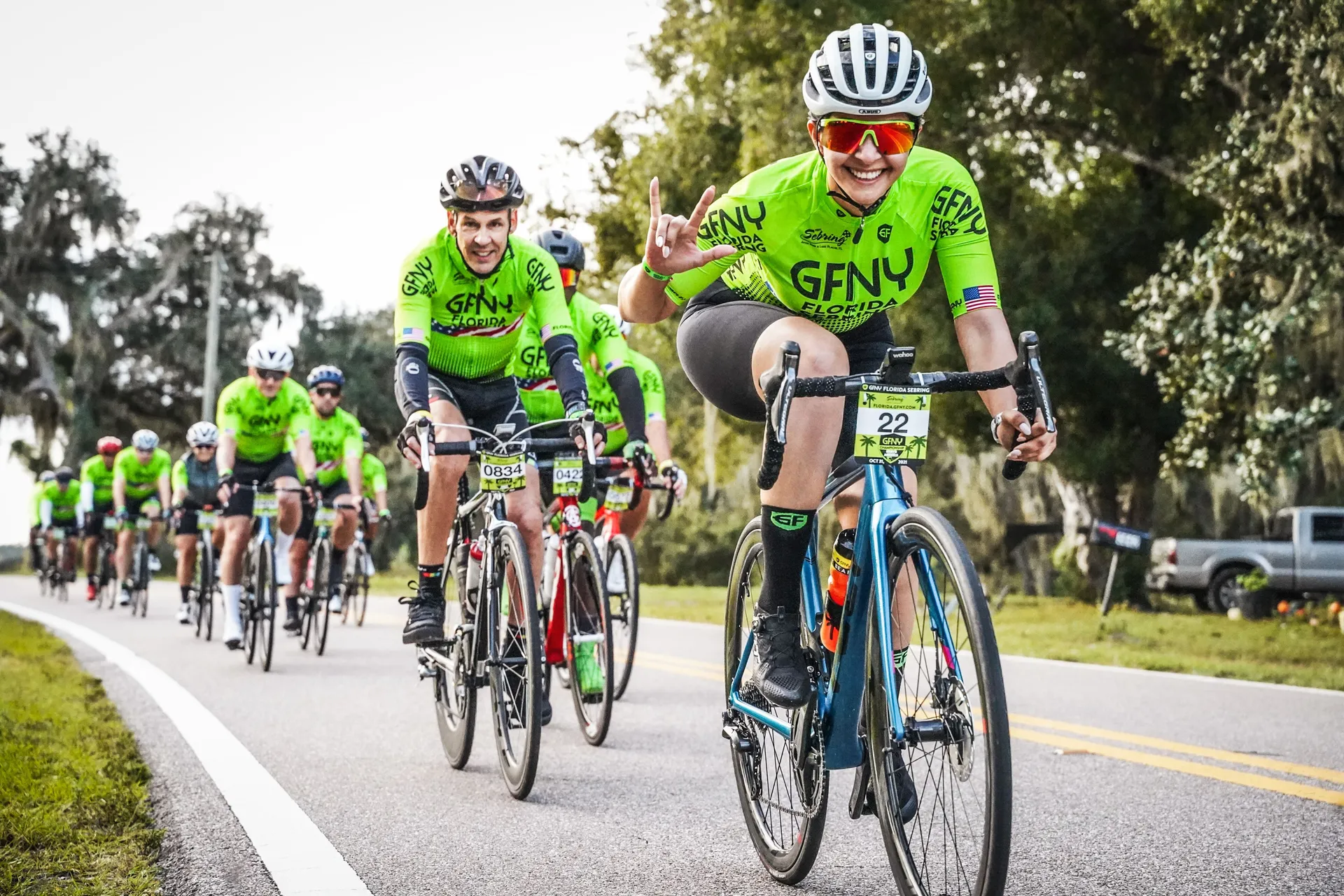This image displays a group of cyclists participating in a road cycling event. The cyclists