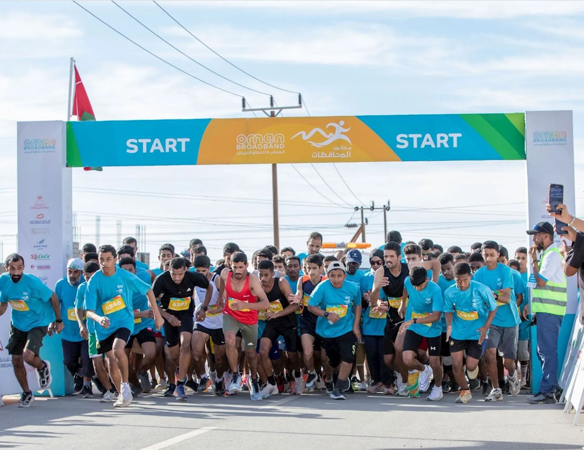 The image shows a group of runners at the start line of a race, about