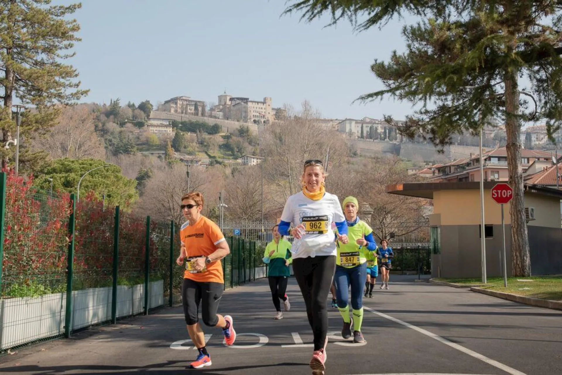 The image shows a group of people participating in a running event during daytime. They