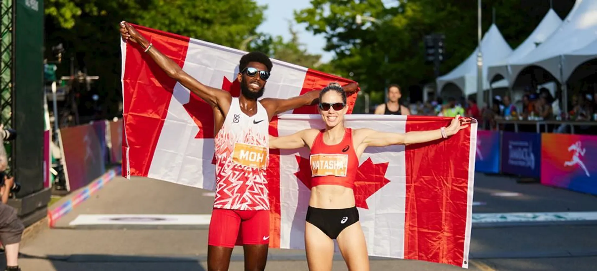 The image features two athletes holding the Canadian flag. Both are dressed in athletic attire