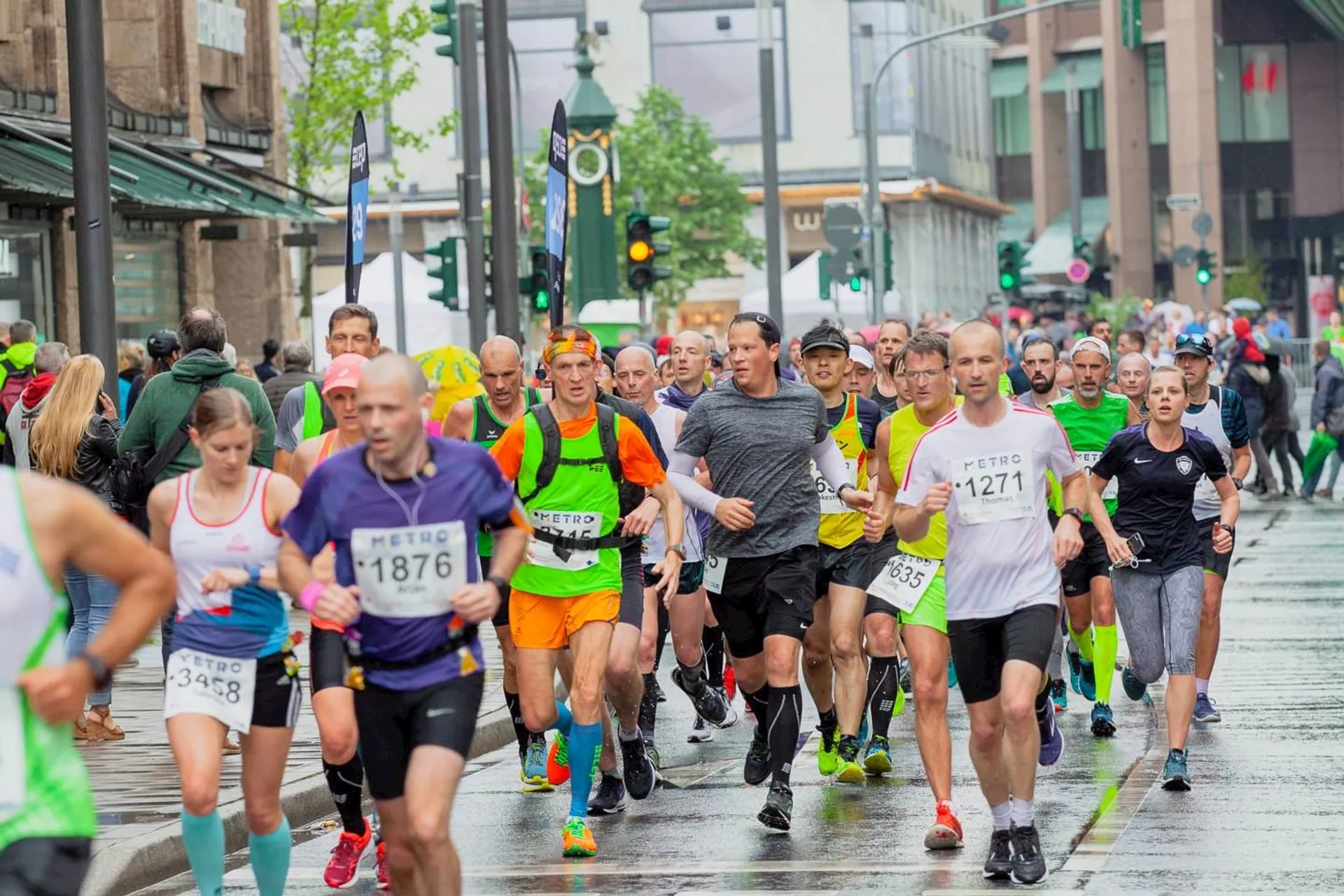 The image shows a large group of runners participating in a road running event. It