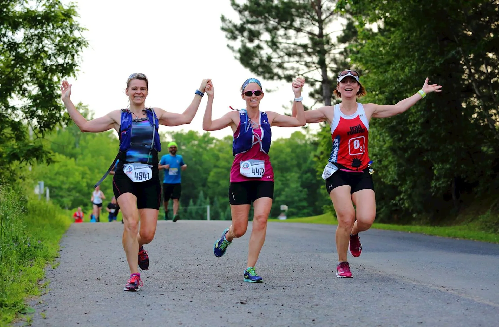 The image shows three women joyfully holding hands and raising their arms in the air
